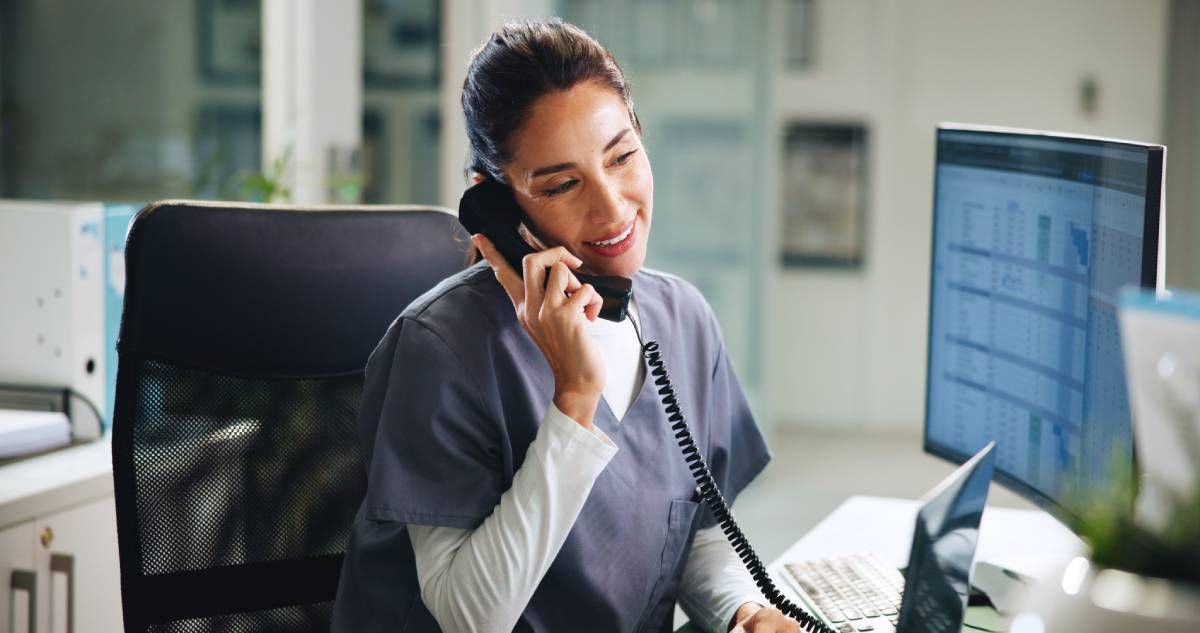 A workplace professional smiling while answering a phone near Edgewood, KY, and Lawrenceburg, IN