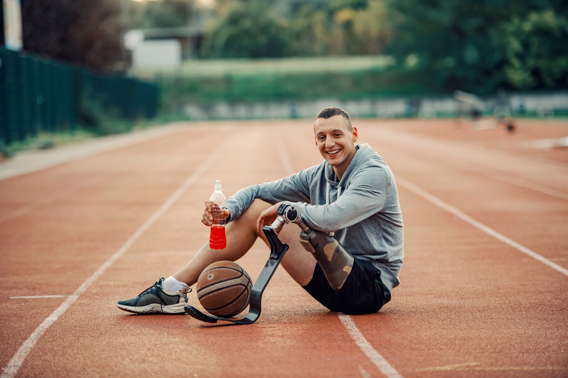 Smiling man with prosthetic leg sitting next to a basketball.