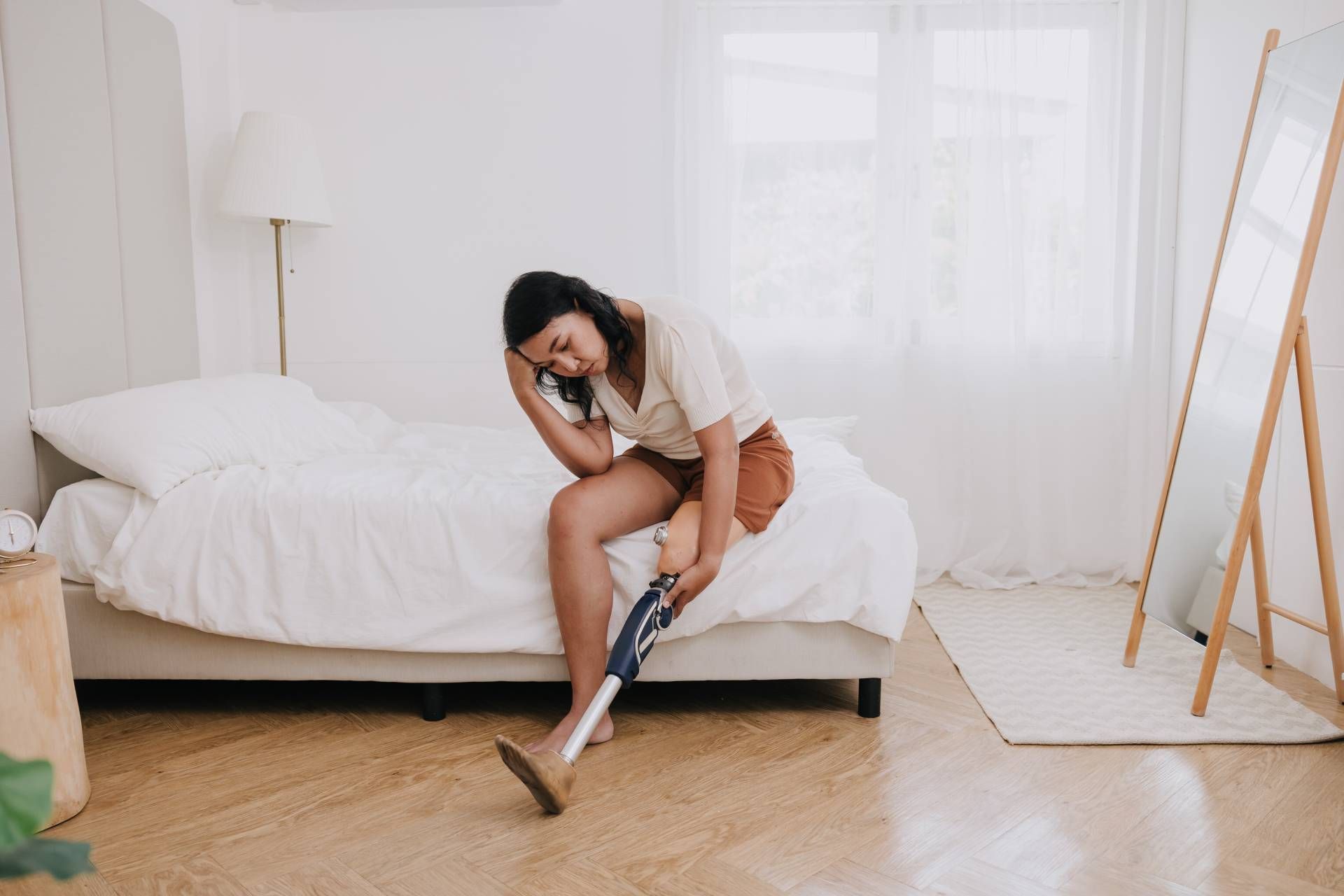 Woman sitting on bed in pain because of prosthesis near Edgewood KY, and Lawrenceburg, IN