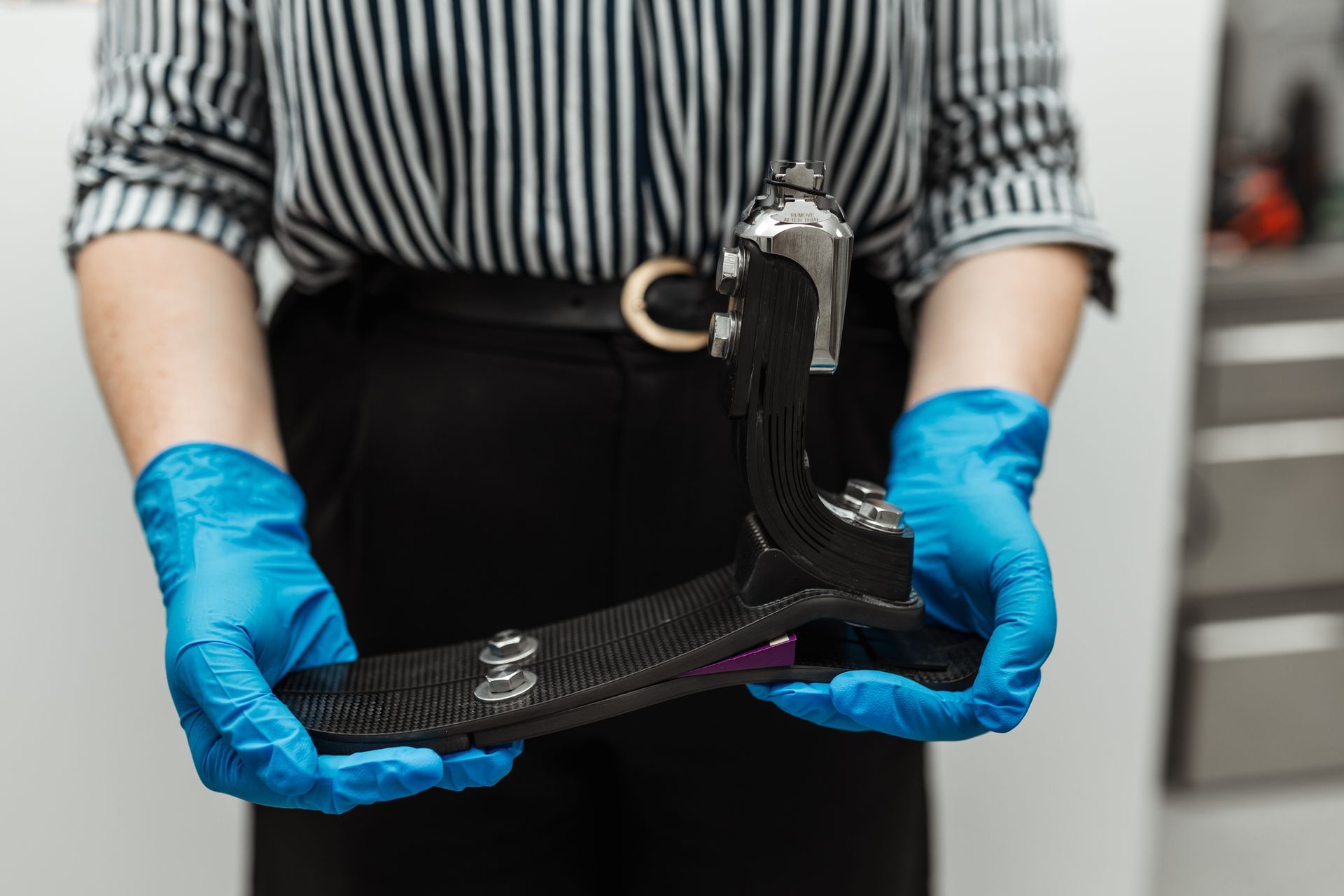 Woman with blue gloves holding dynamic response foot prosthetic.