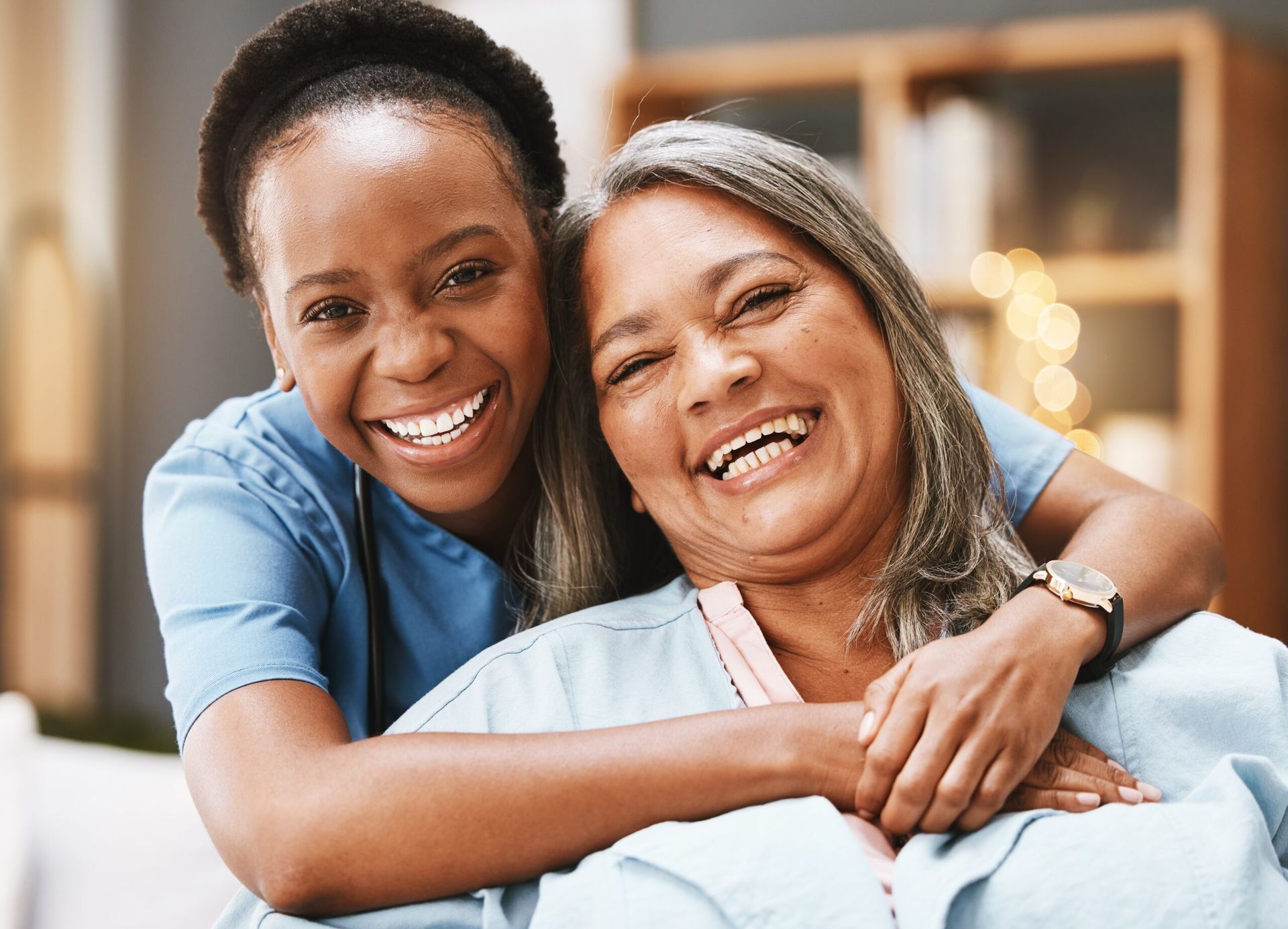 Two smiling women embracing on a couch in a cozy living room