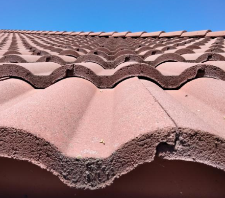 A close up of a tiled roof with a blue sky in the background