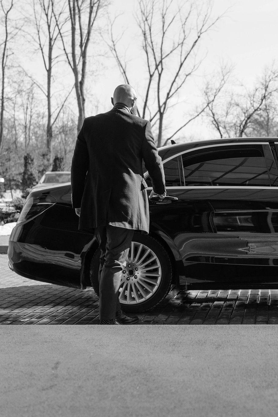 A black and white photo of a man getting out of a car