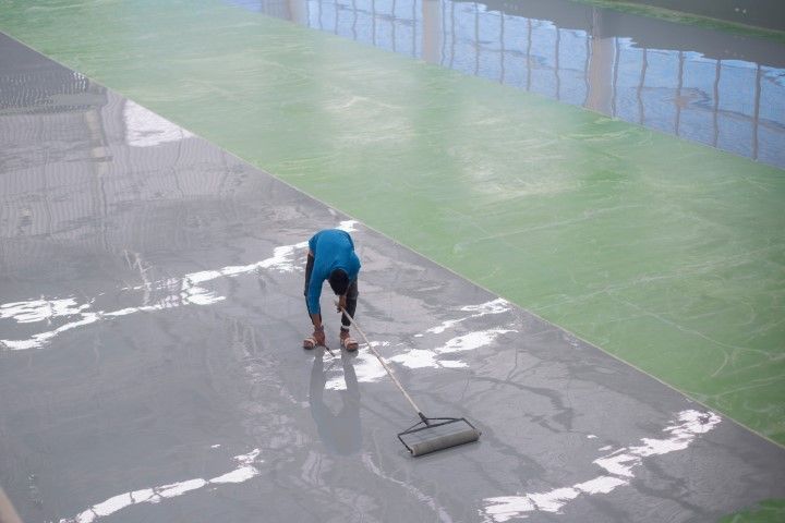 A man is cleaning the floor of a building with a broom.