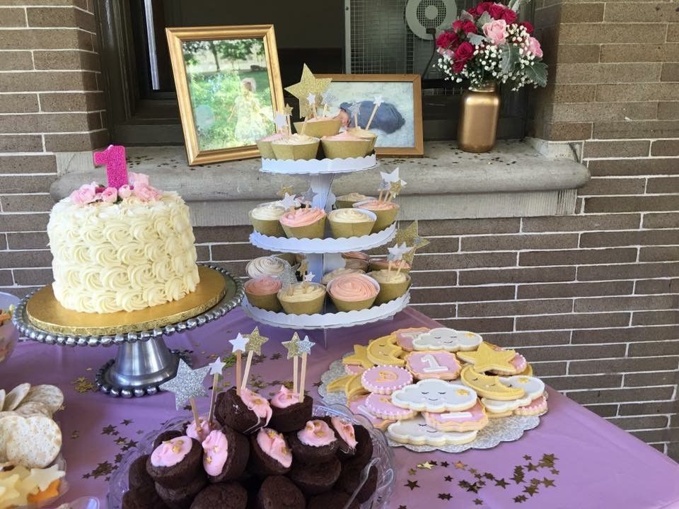 Dessert table with cakes, cupcakes, and cookies on a purple tablecloth at an outdoor event