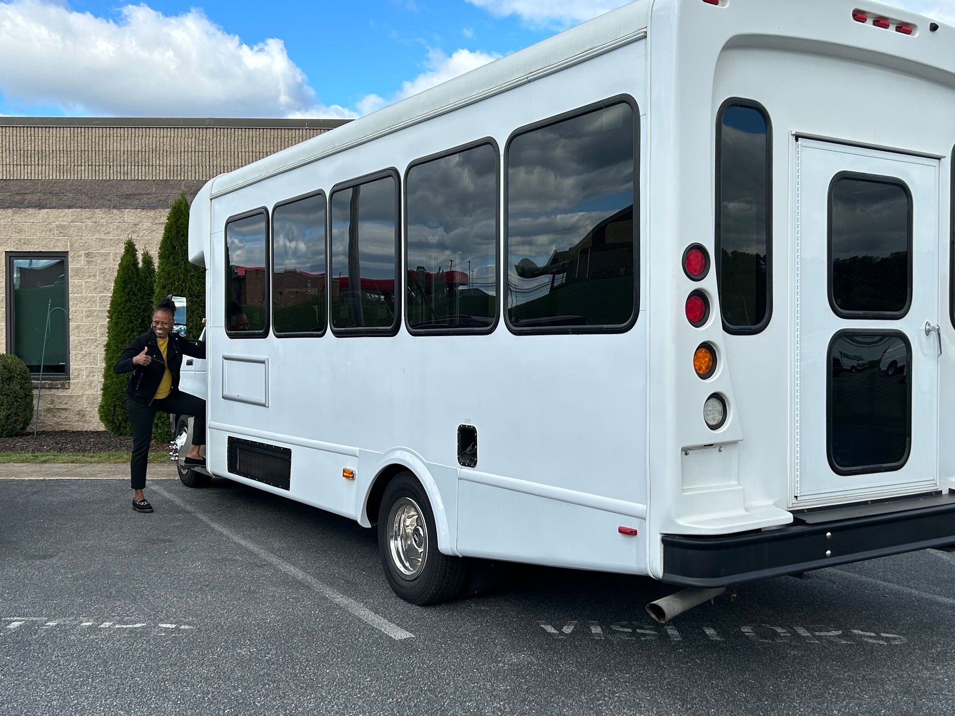 White shuttle bus parked outdoors with a person standing by the side door