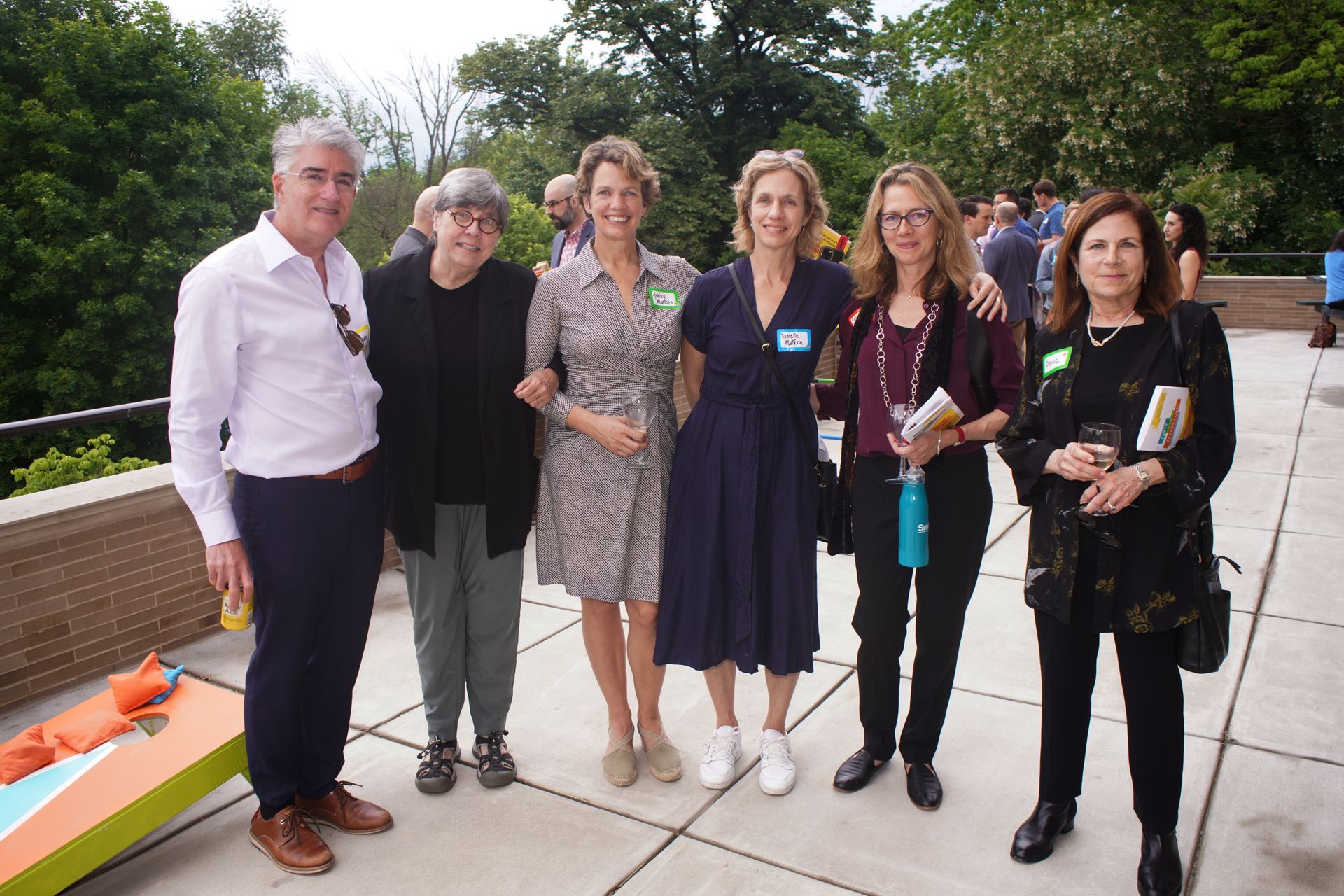 Six people standing together outdoors on a sidewalk, posing for a group photo.
