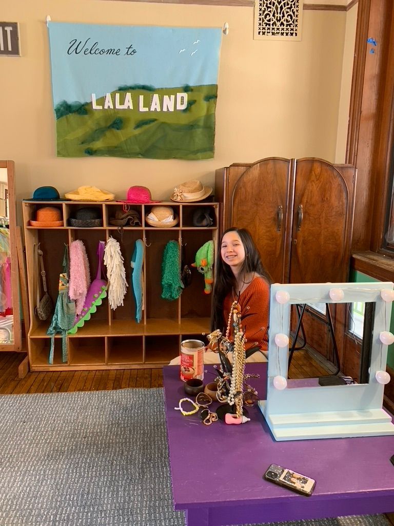 Woman sitting by purple table in a colorful classroom display labeled “La La Land”