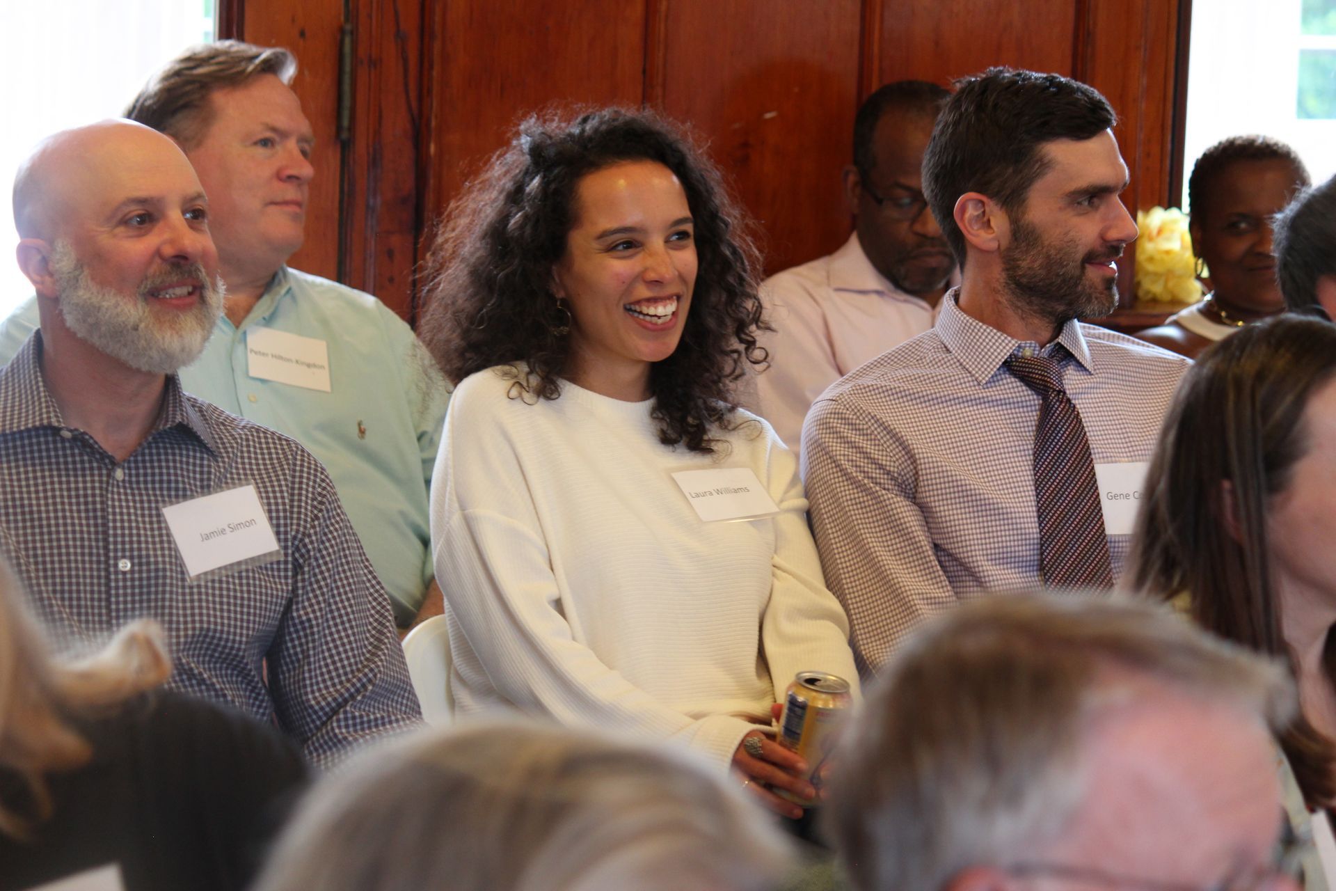 Audience members seated indoors, smiling and listening during an event