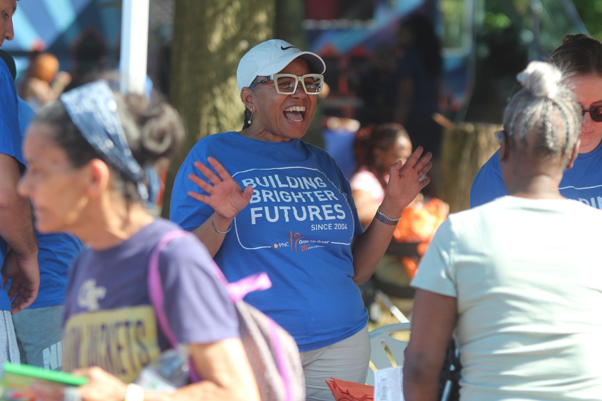 Woman in blue shirt and cap smiling at a street rally, holding a sign that reads “Bright Futures.”