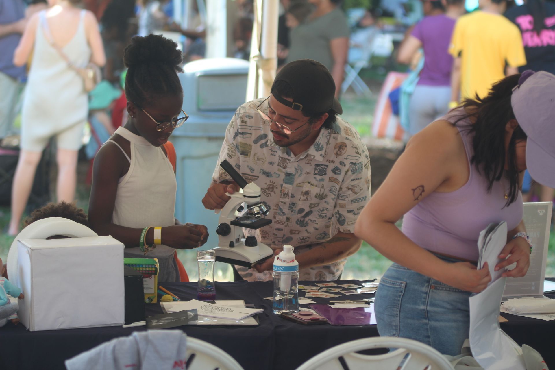 People browsing handmade items at an outdoor market table with crafts and accessories