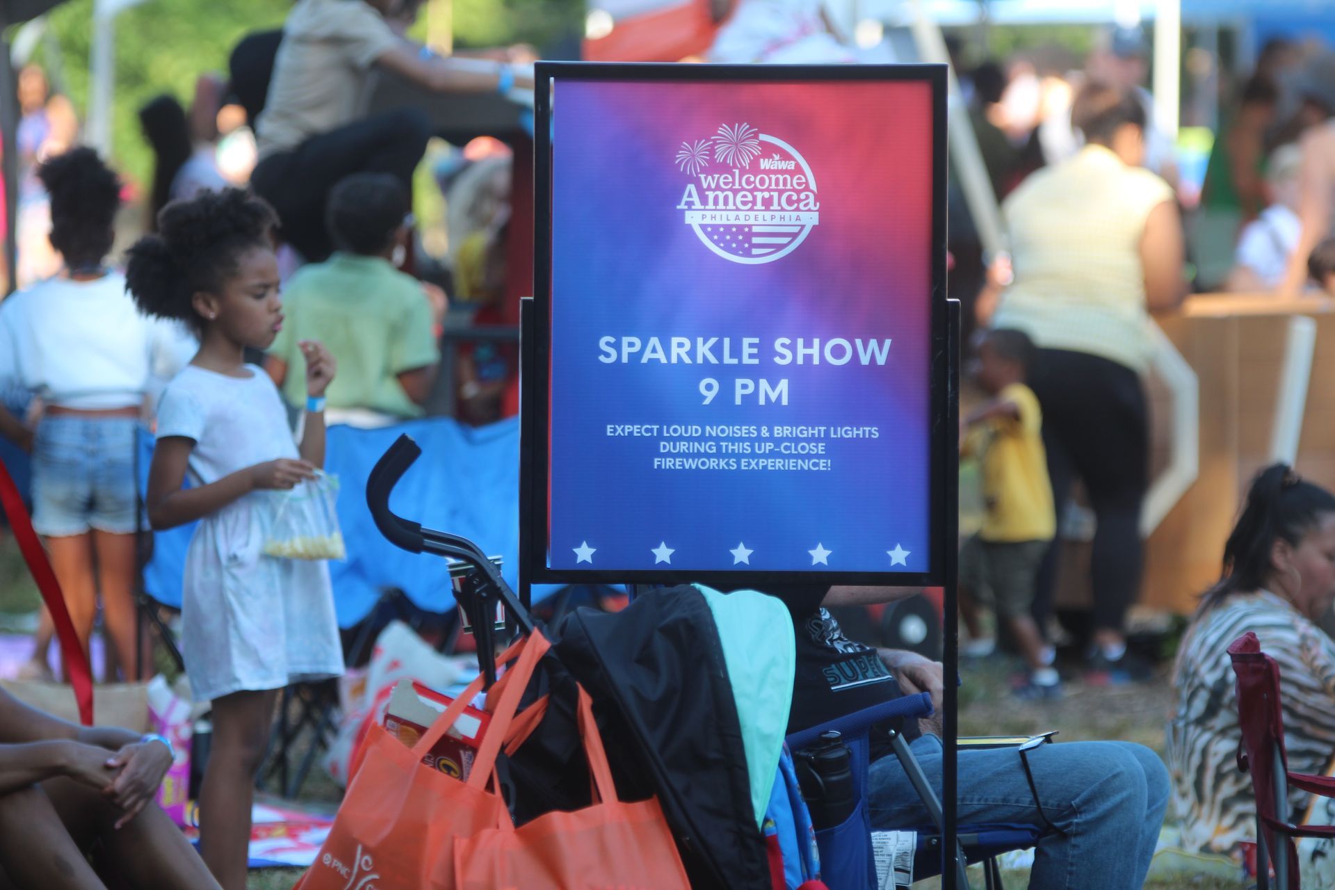 Sign advertising “Sparkle Show” at 9 PM in a busy outdoor crowd