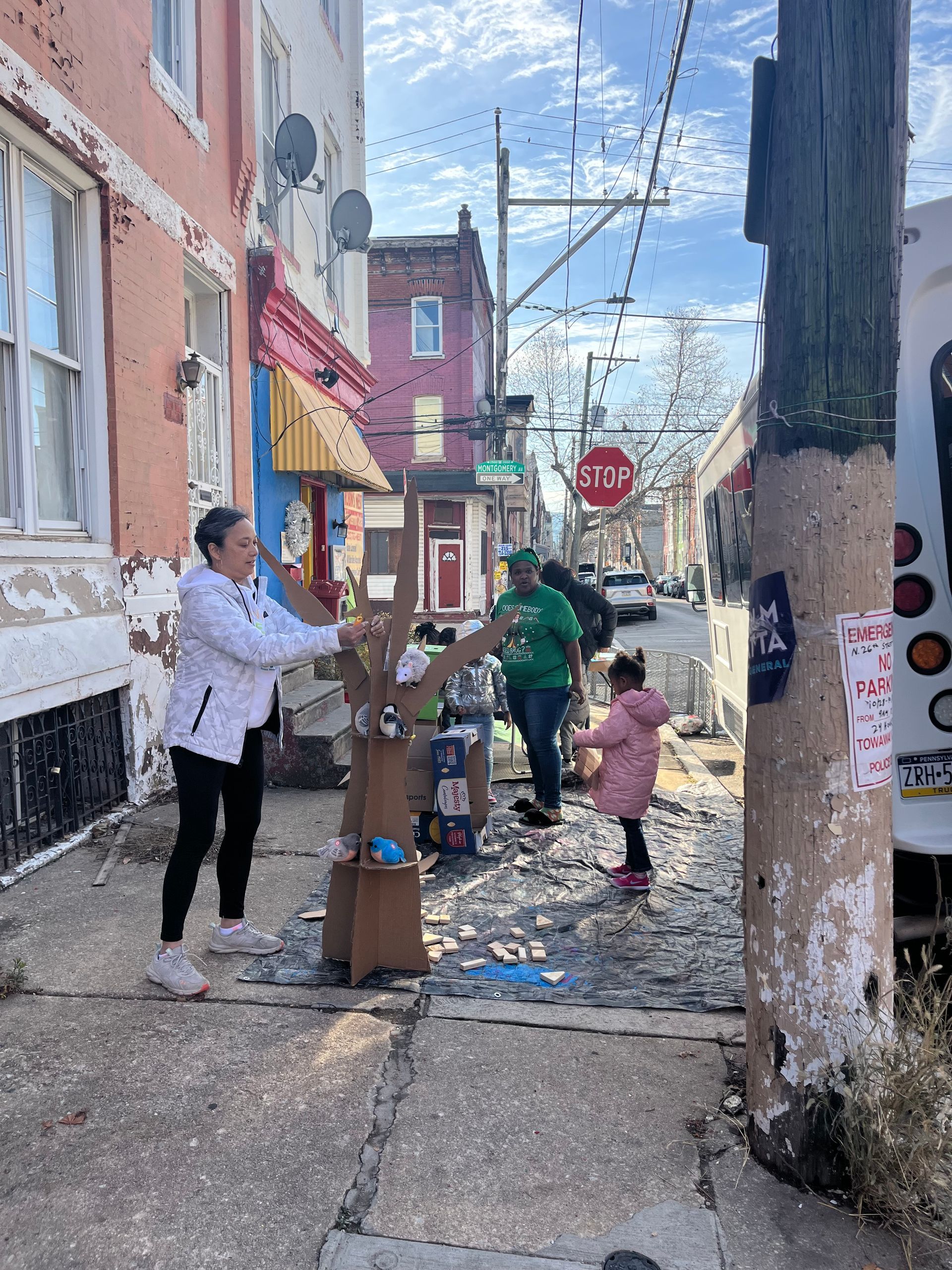 People walking through a narrow alley with scattered debris, colorful buildings, and a red stop sign ahead.
