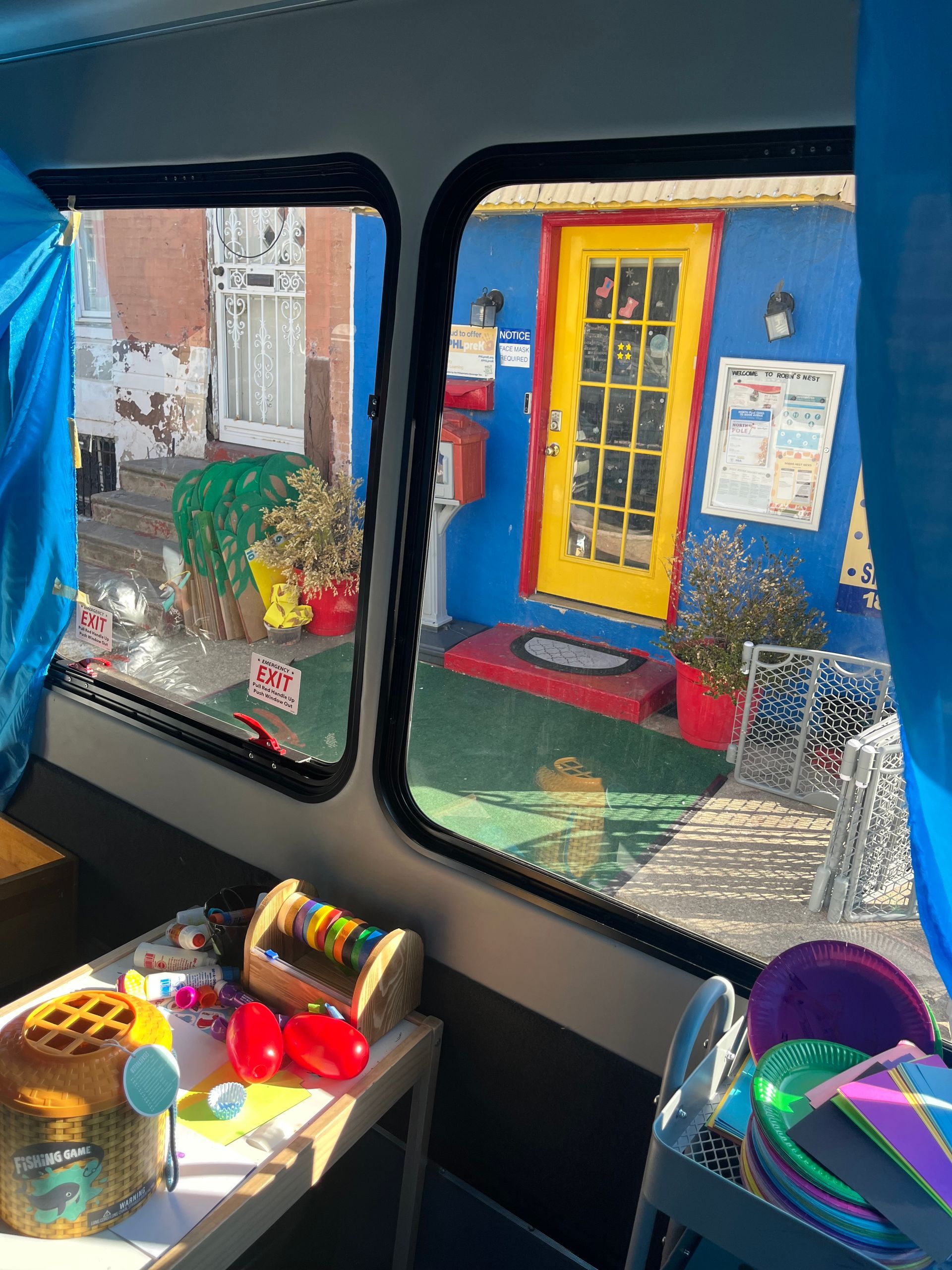Colorful children’s play area with toy bins, seen through a van or bus window.