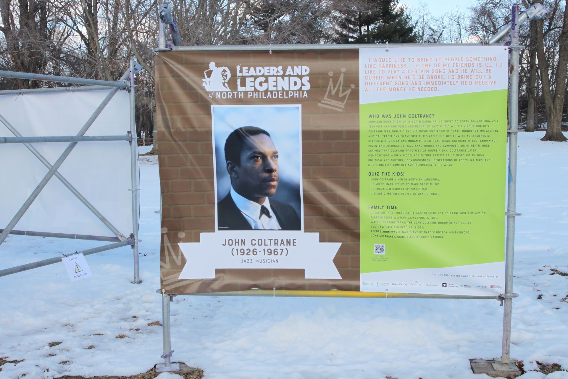 Outdoor display board in snow, featuring a portrait poster and green event text panel.