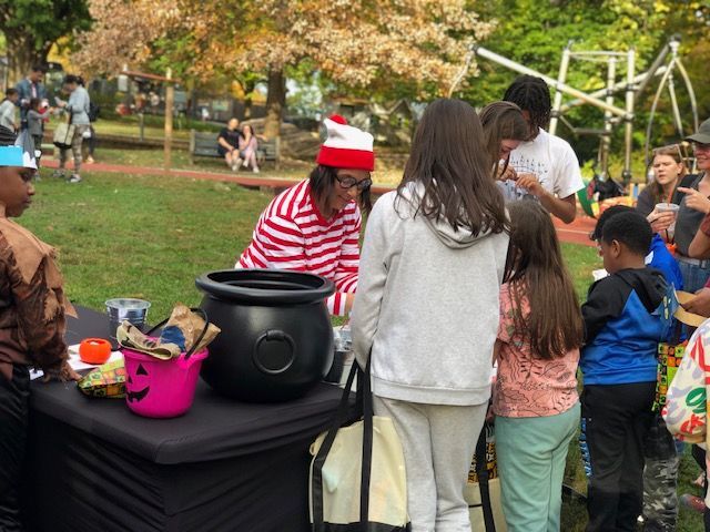 People gathered at a park table with a black pot and festive red-and-white hat.