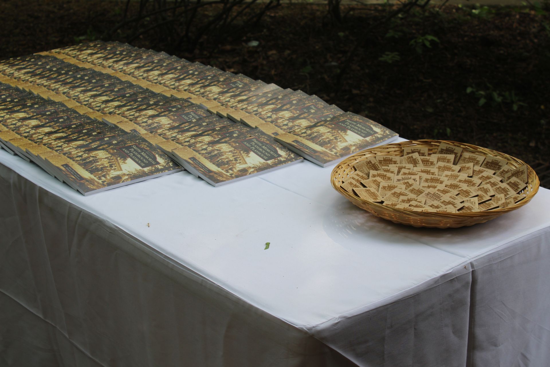 Table with several wrapped bread loaves and a round woven basket on a white cloth outdoors