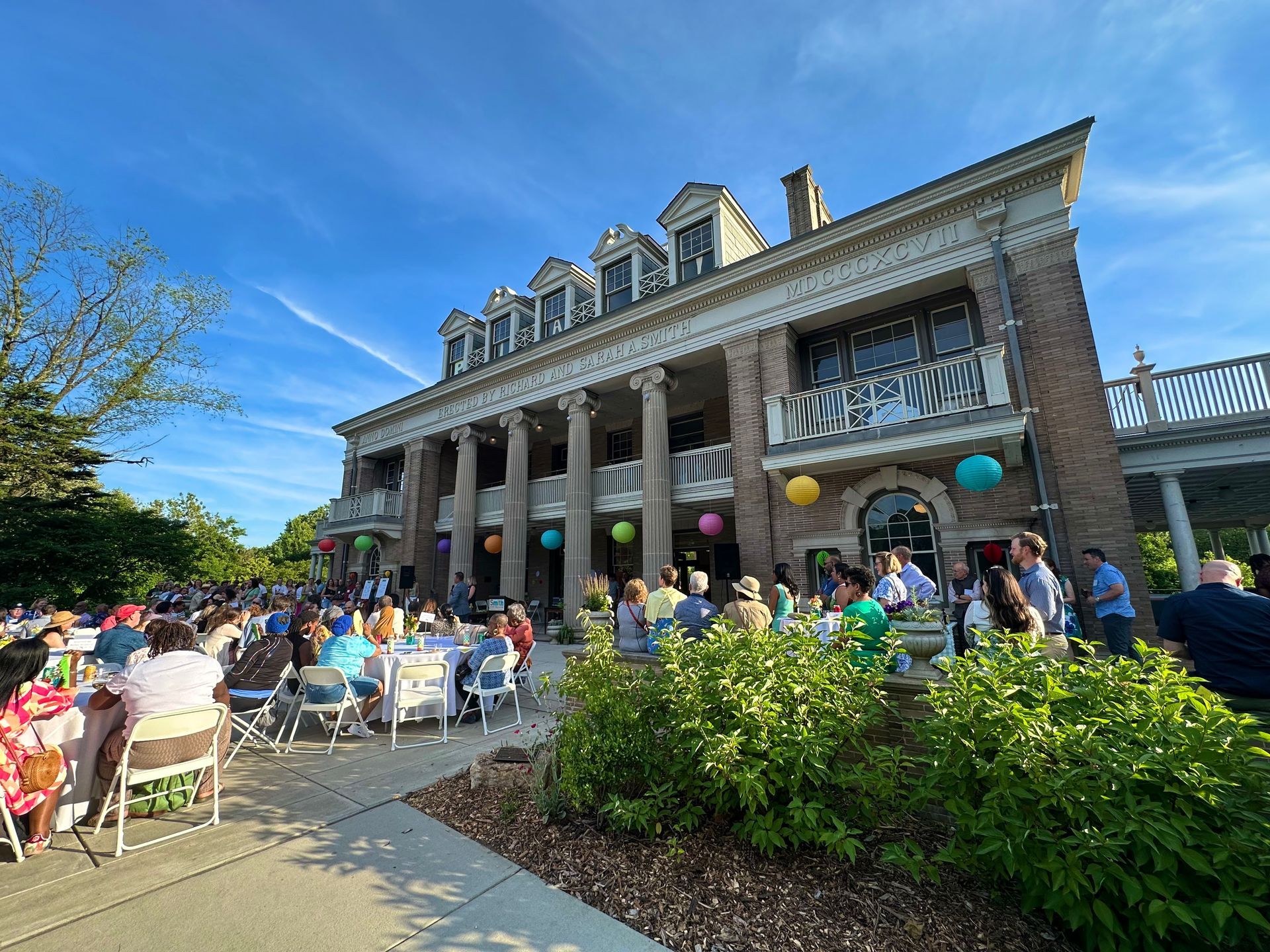 Outdoor café crowd outside a grand stone building with columns and blue sky