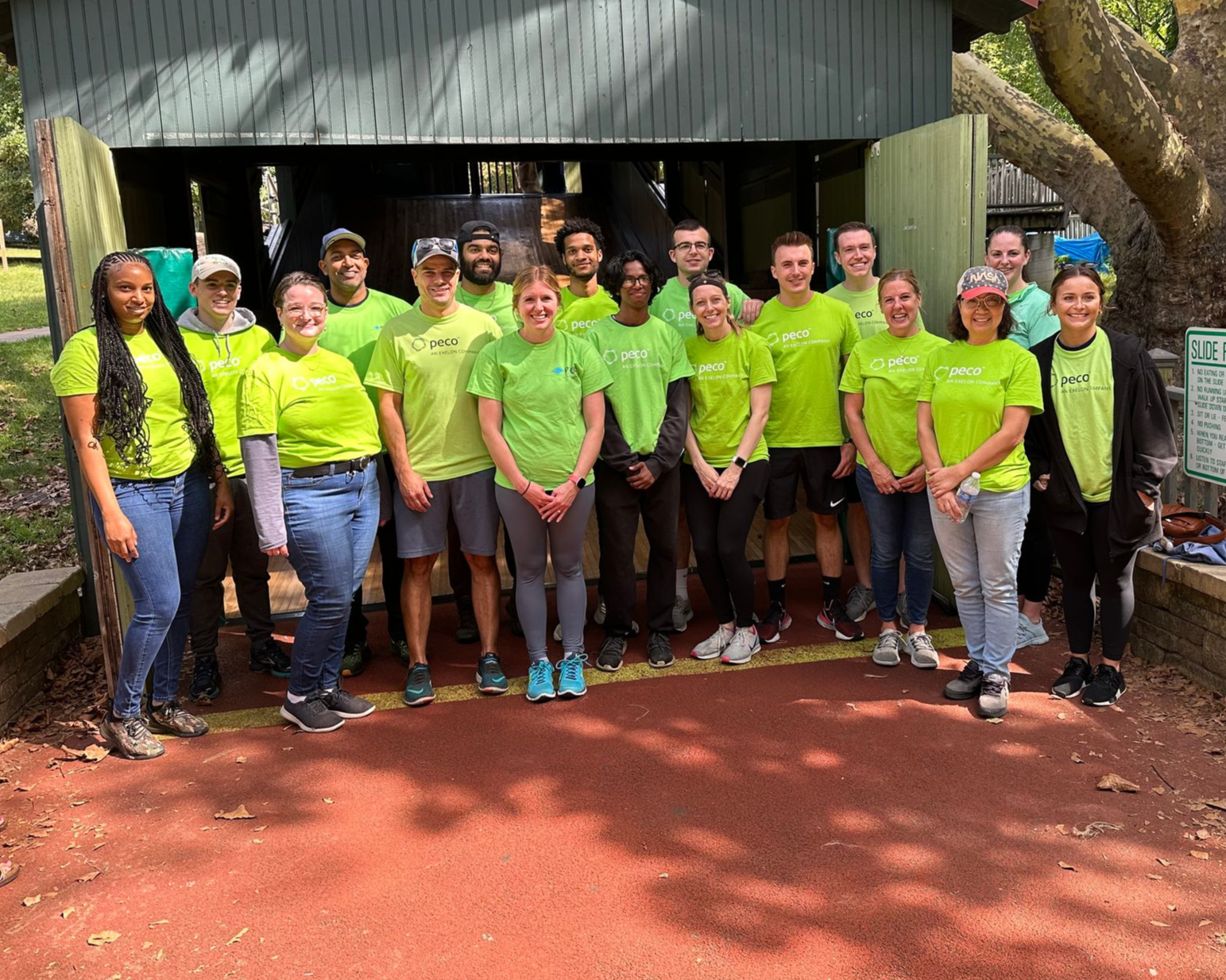 Group of people in neon green shirts standing outdoors in front of a building