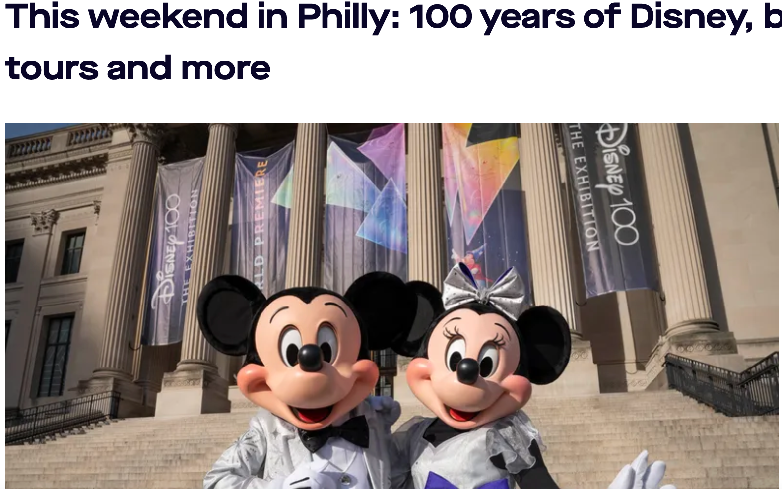 Mickey and Minnie Mouse in front of banners at a Disney 100 exhibit building