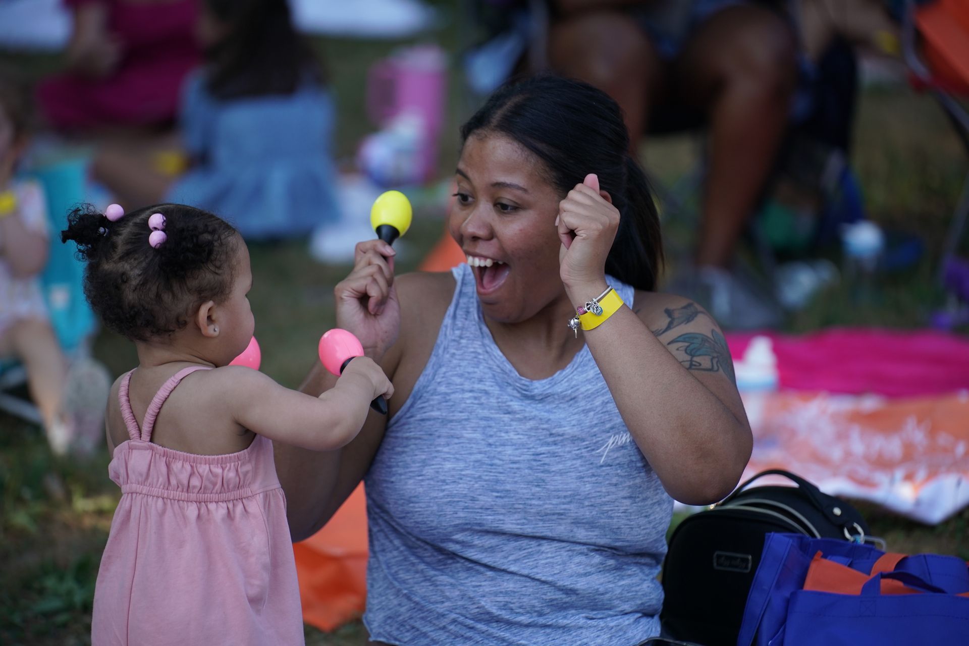 Child offering a toy microphone to a smiling woman at an outdoor event