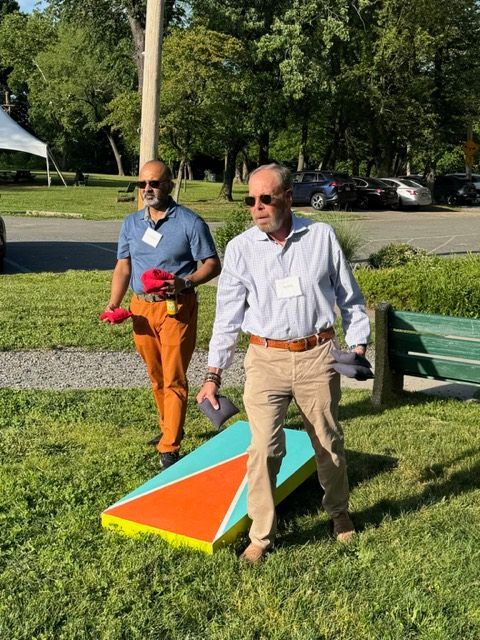 Two men standing on grass near a colorful triangular marker in a park