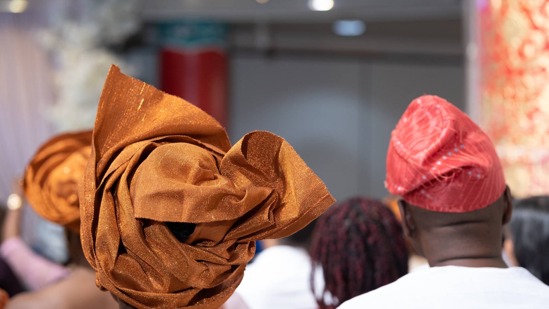 A man wearing a red hat is standing next to another man wearing a brown hat.