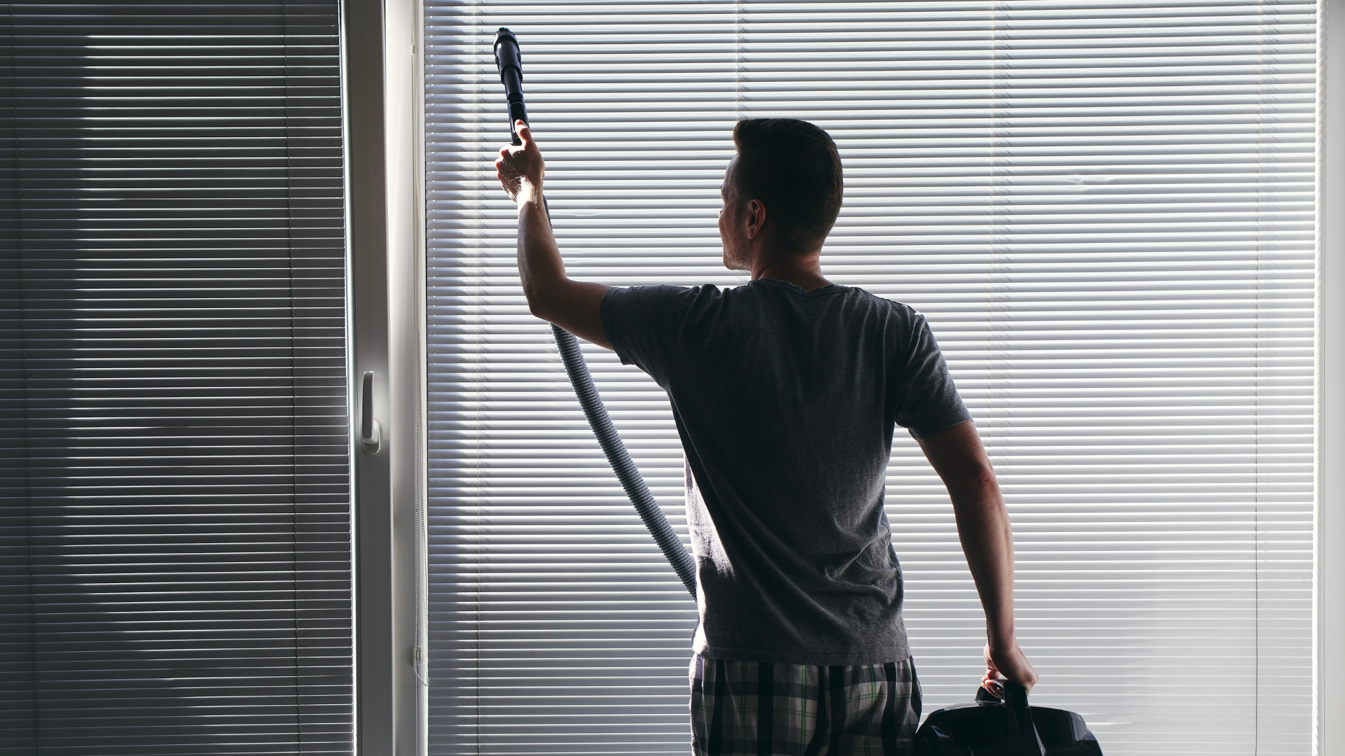 A man is cleaning a window with a vacuum cleaner.