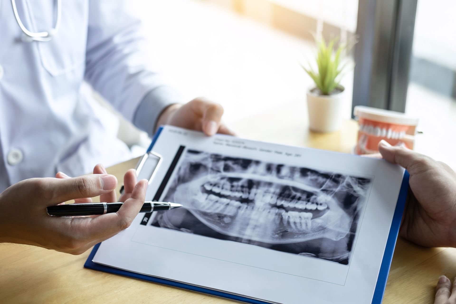 Dentist showing a patient a dental X-ray on a clipboard in a bright clinic office