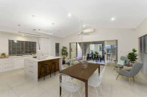 Open-concept Kitchen and Dining Area With White Cabinets, Dark Wood Table, and Chairs — George Pappas Painting In Buderim, QLD