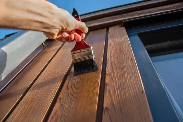 Person Applying Wood Stain With a Brush to Wooden Siding — George Pappas Painting In Buderim, QLD
