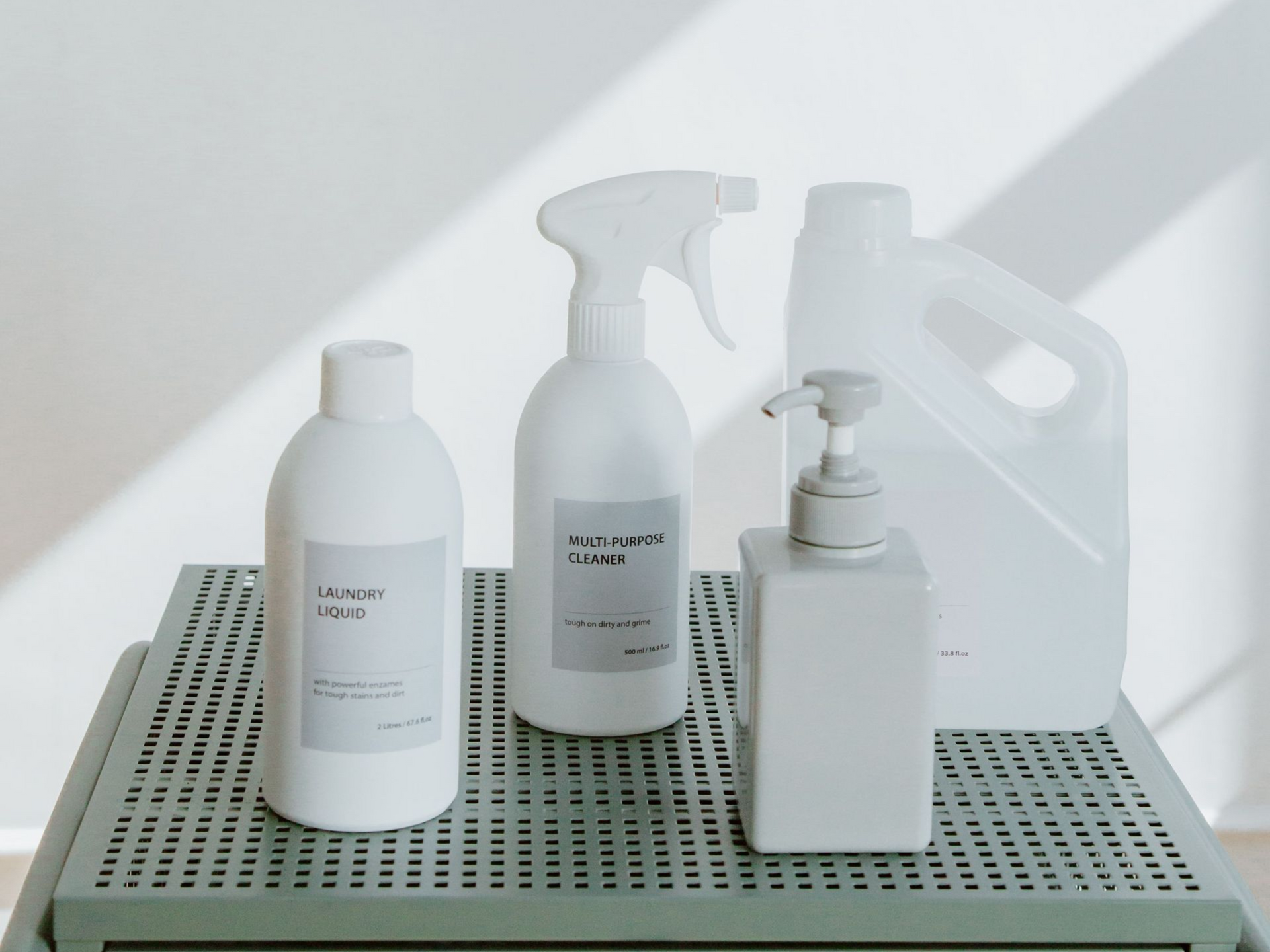 Assorted cleaning product bottles on a perforated shelf against a light background