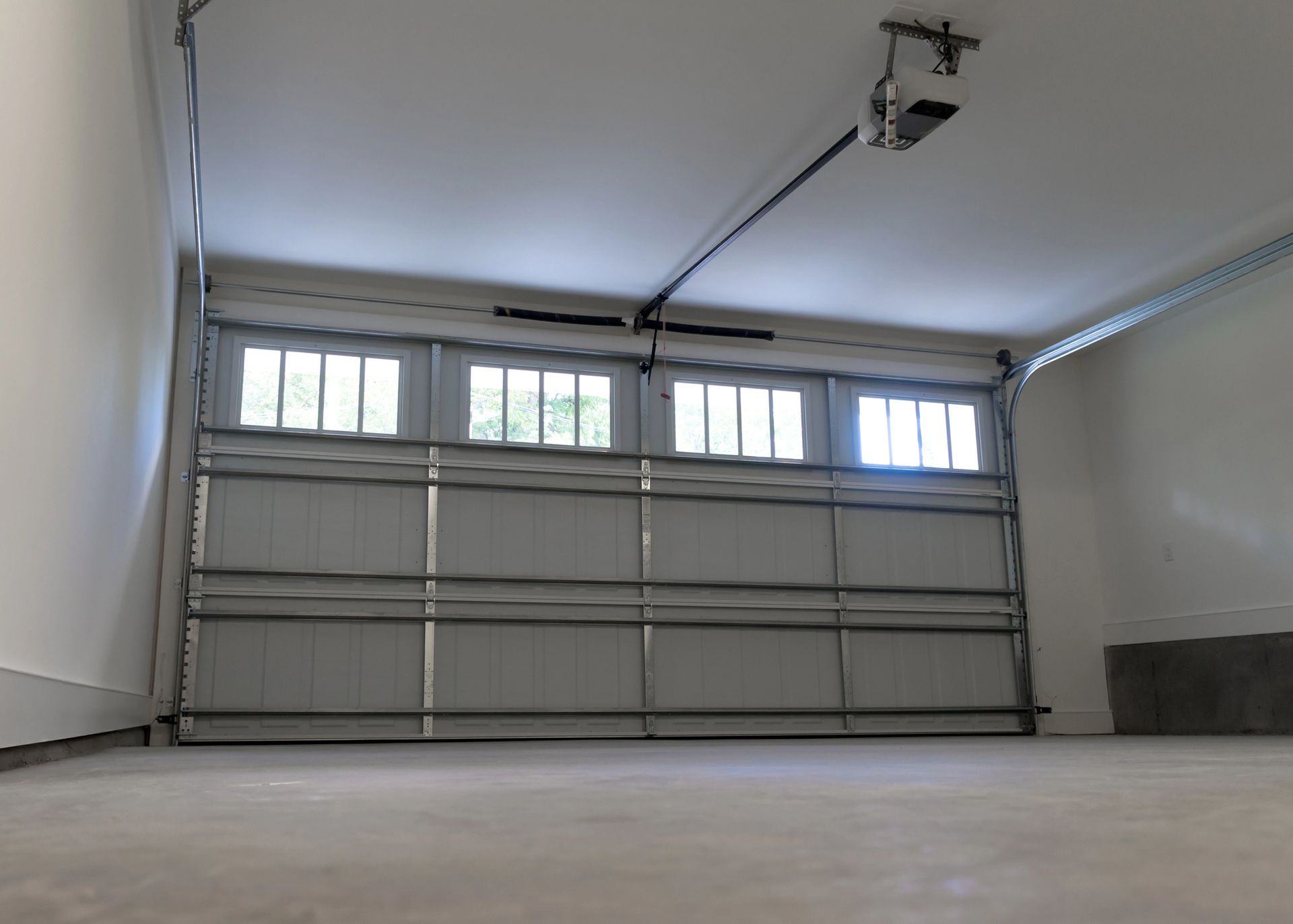 Empty garage with a closed metal door and small windows near the ceiling.