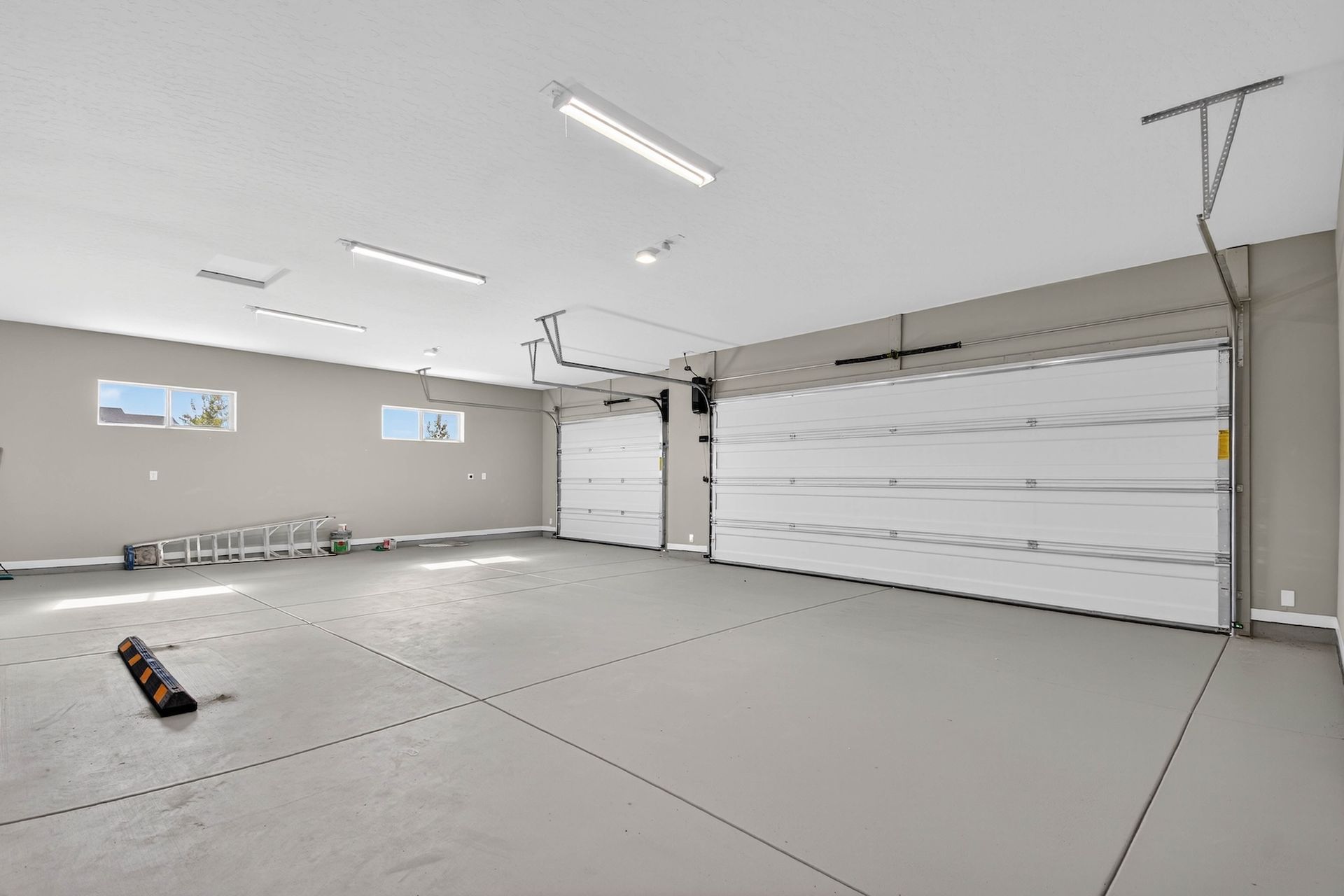 Empty modern garage interior with white walls, concrete floor, and overhead lighting