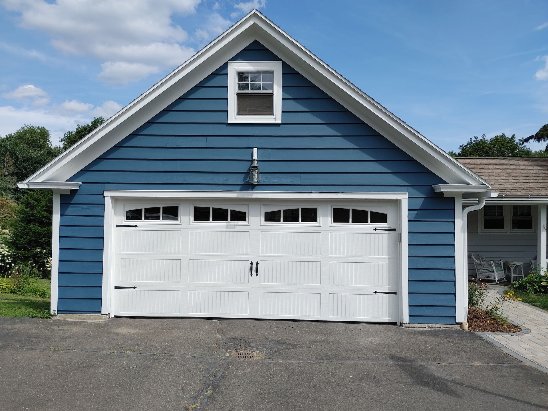 Blue house with white garage doors and trim, front view with paved driveway.