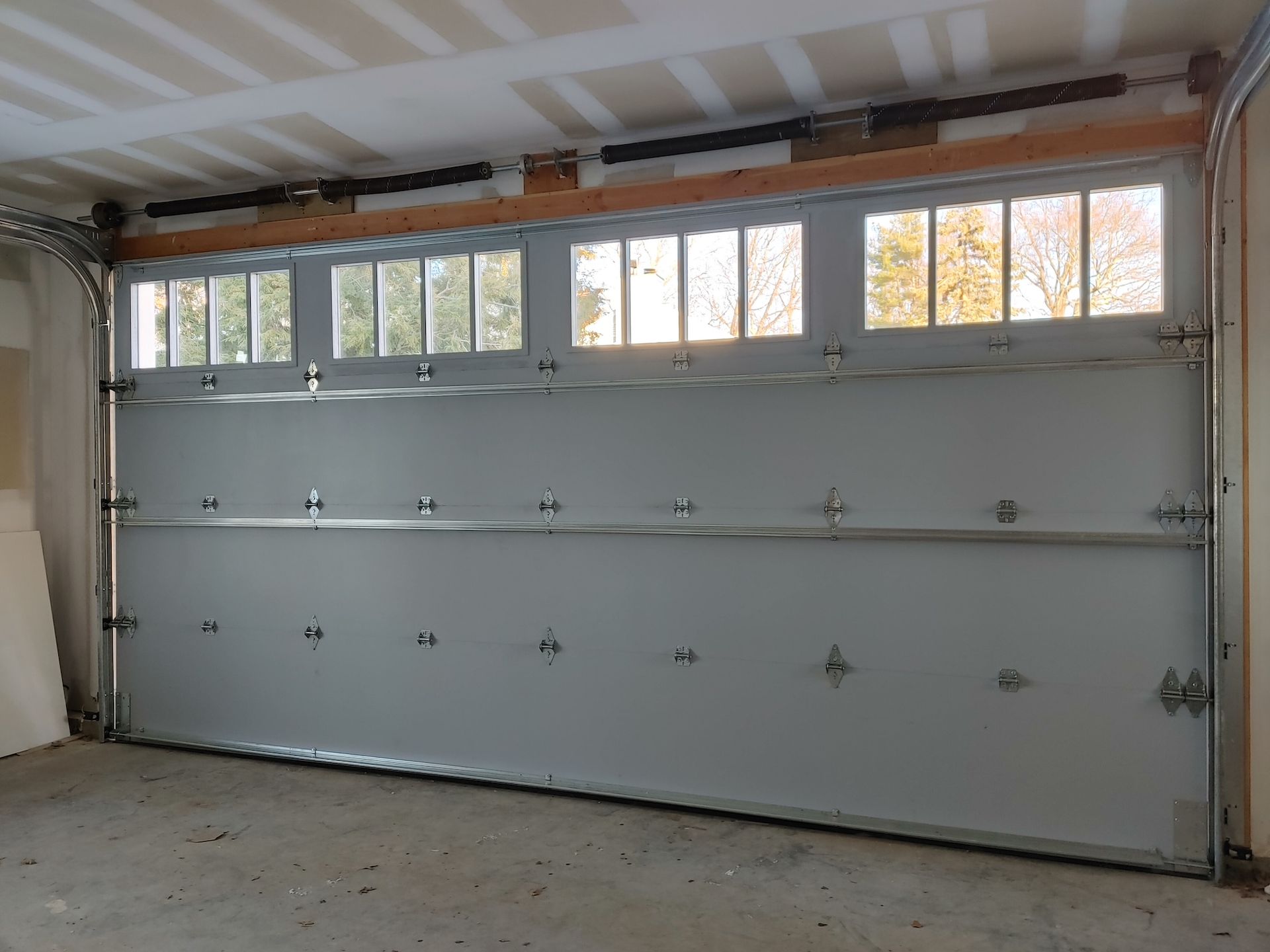 Empty garage with a closed white sectional door and small windows along the top.