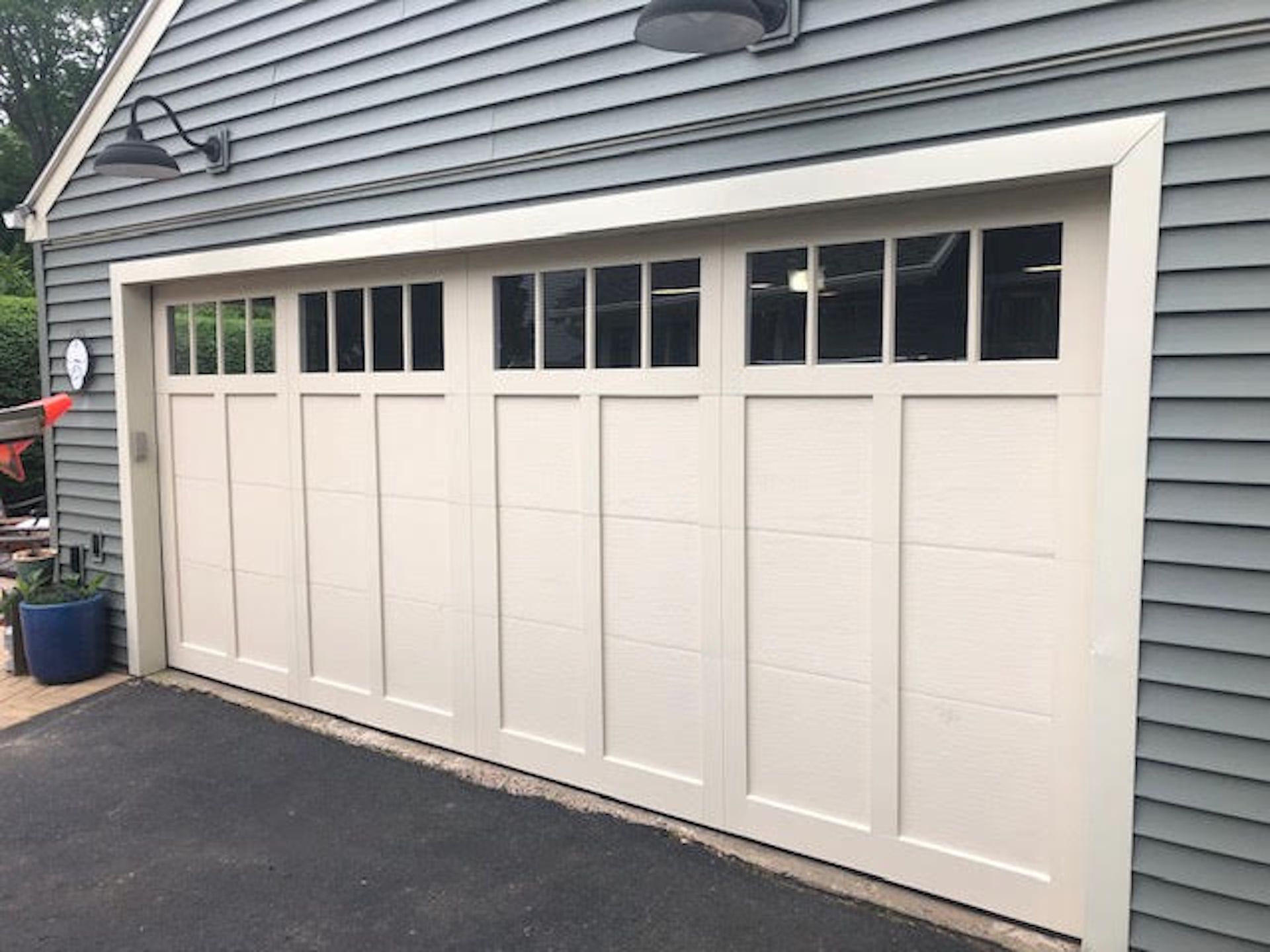 White garage doors with small windows on a gray house exterior