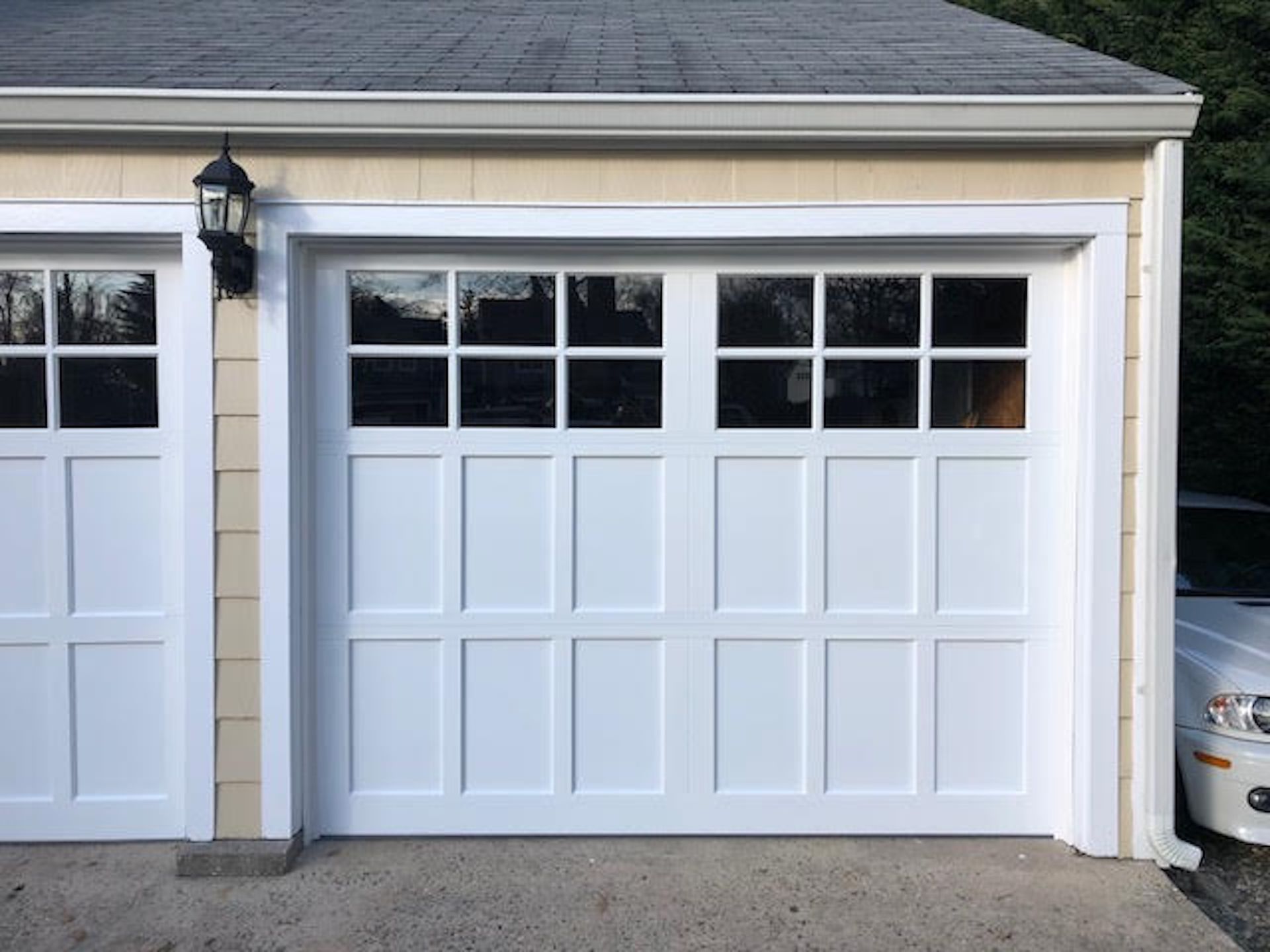 White garage door with window panes on a beige house exterior