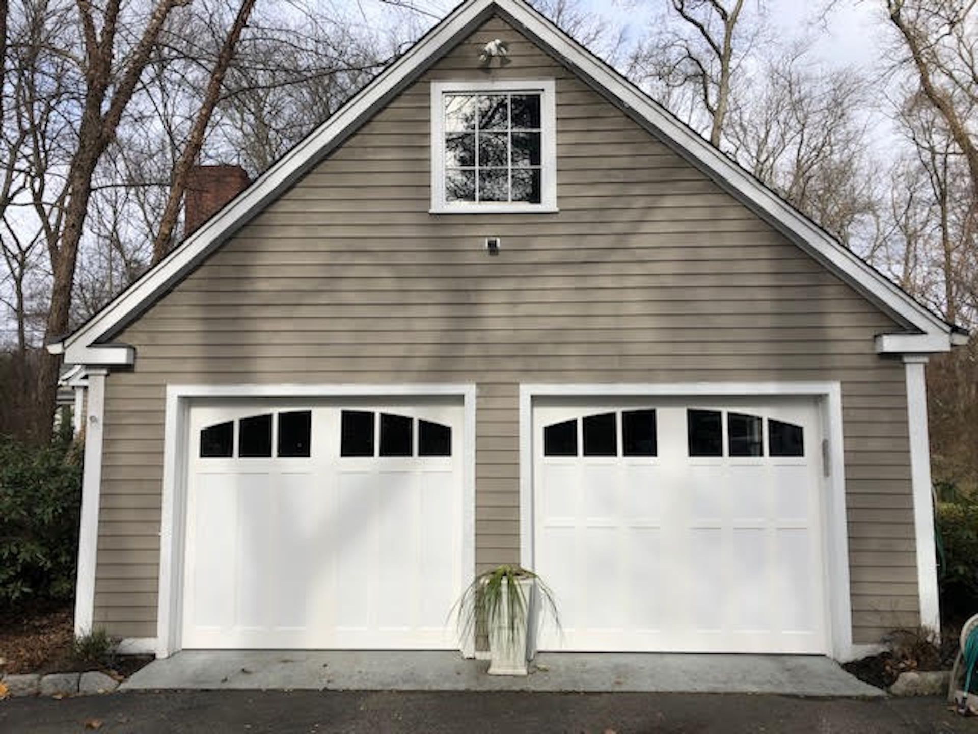 Two-car white garage with gray siding and a small window above the doors