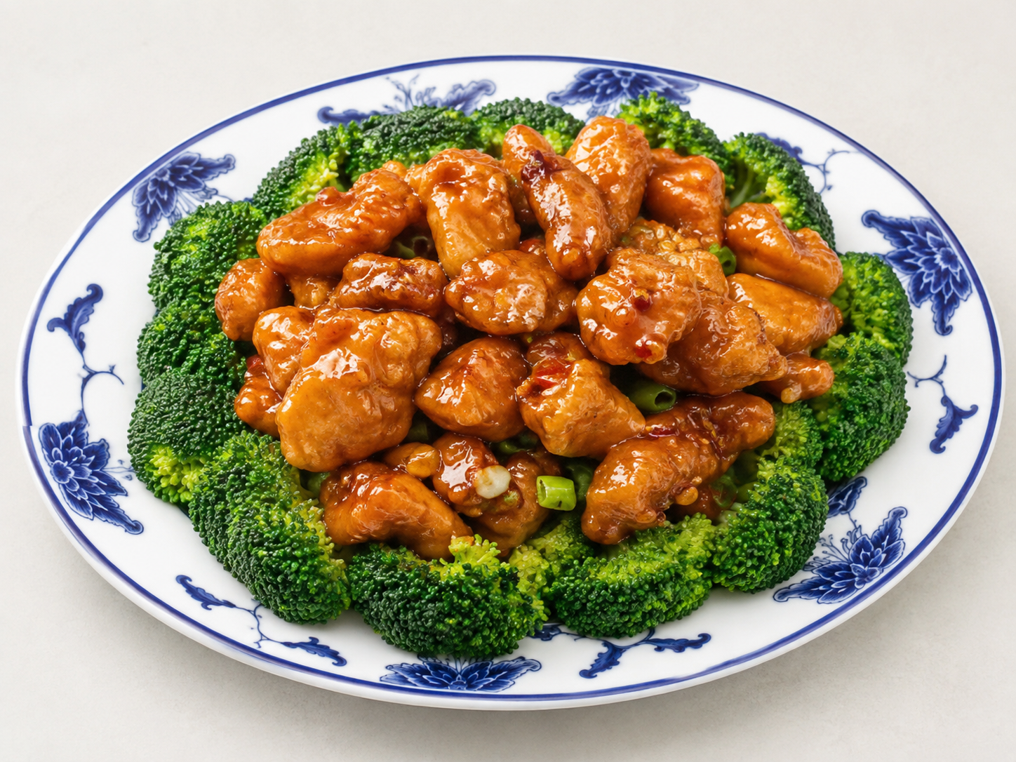 Glazed chicken pieces on a white plate, surrounded by broccoli florets