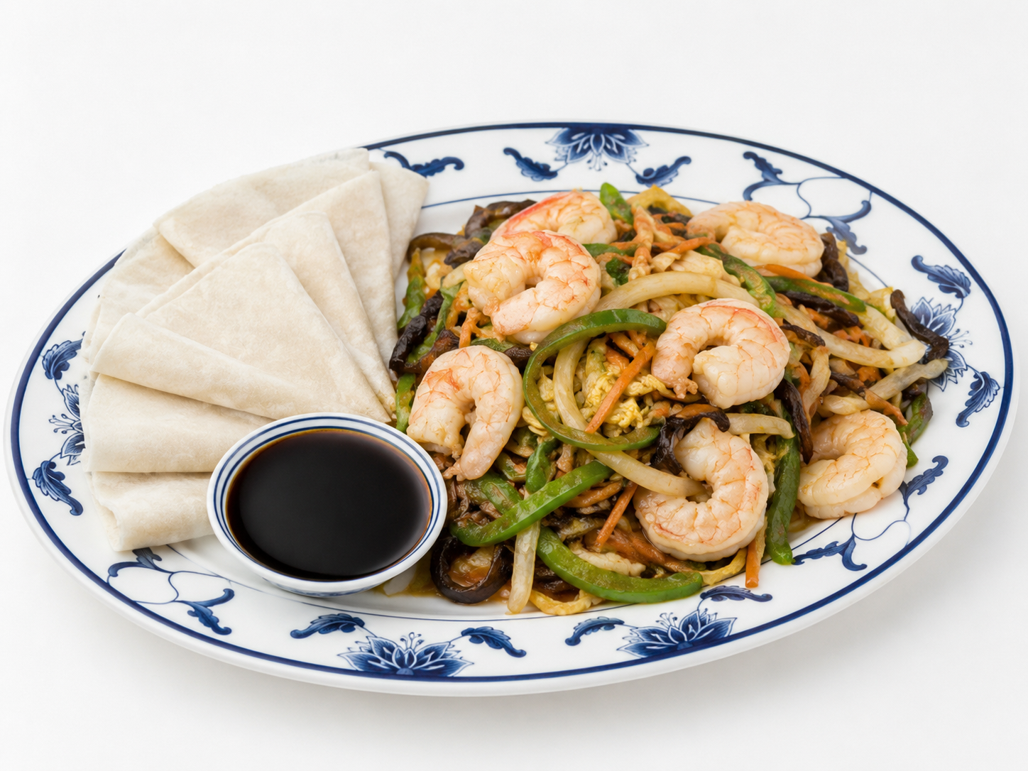 Shrimp stir-fry on a blue-and-white plate with folded crepes and a small bowl of dark sauce