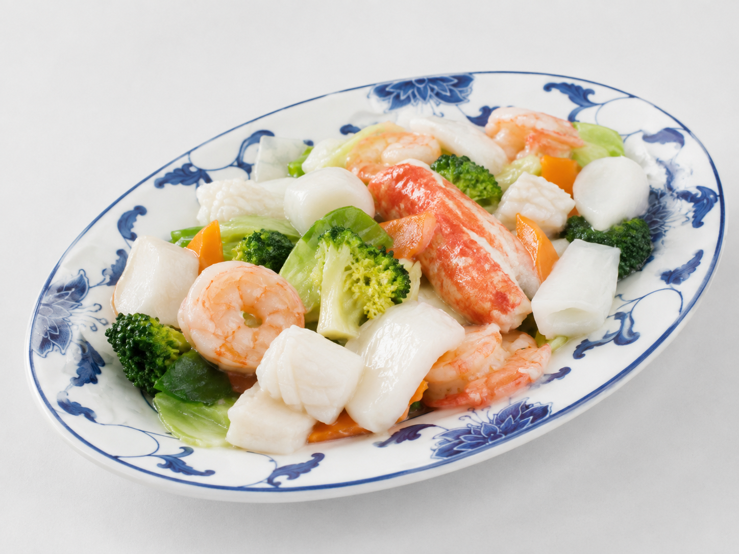 Mixed vegetable and shrimp stir-fry on a white and blue oval plate