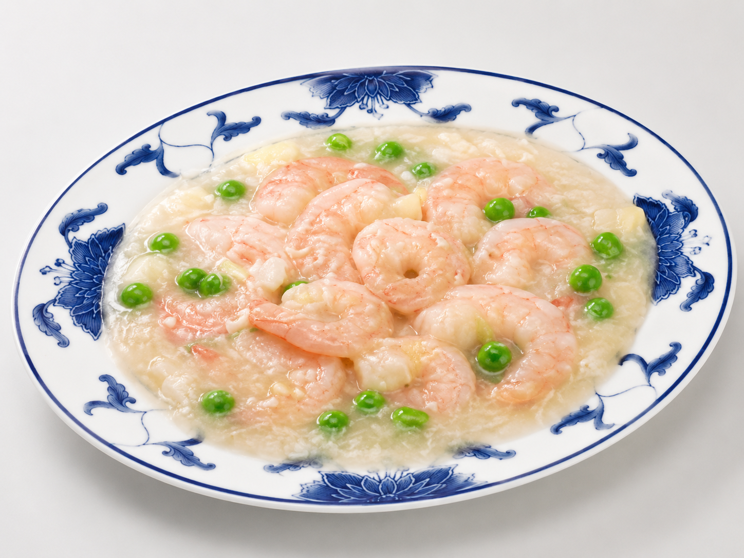 Shrimp and peas in a creamy sauce served on a blue-and-white oval plate