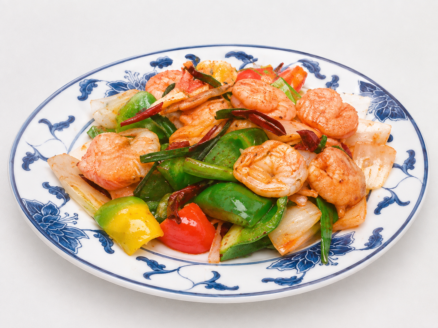 Plate of shrimp stir-fry with colorful vegetables on a blue-and-white dish