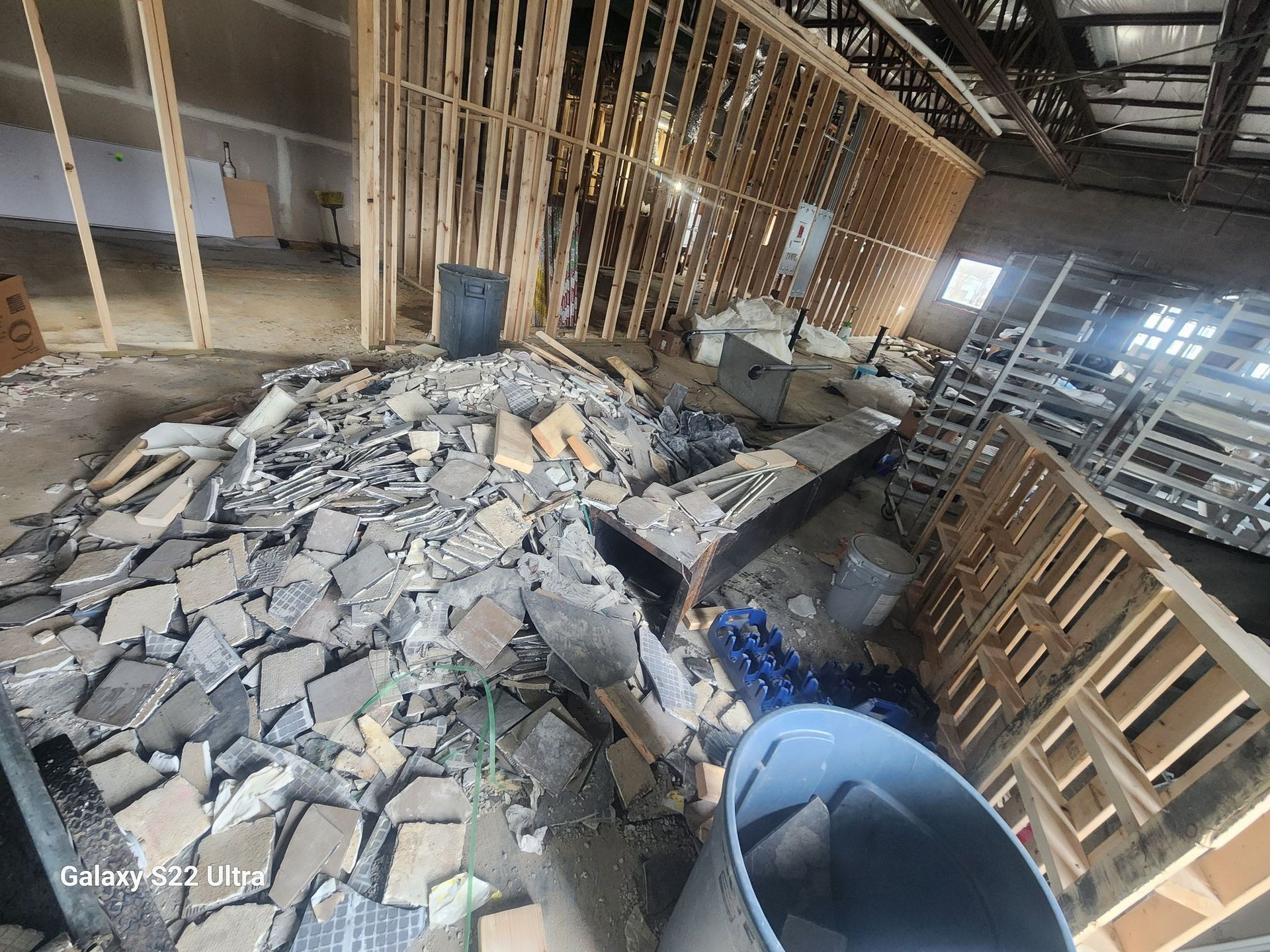 Collapsed interior with piles of rubble, exposed framing, and scattered debris in a damaged building