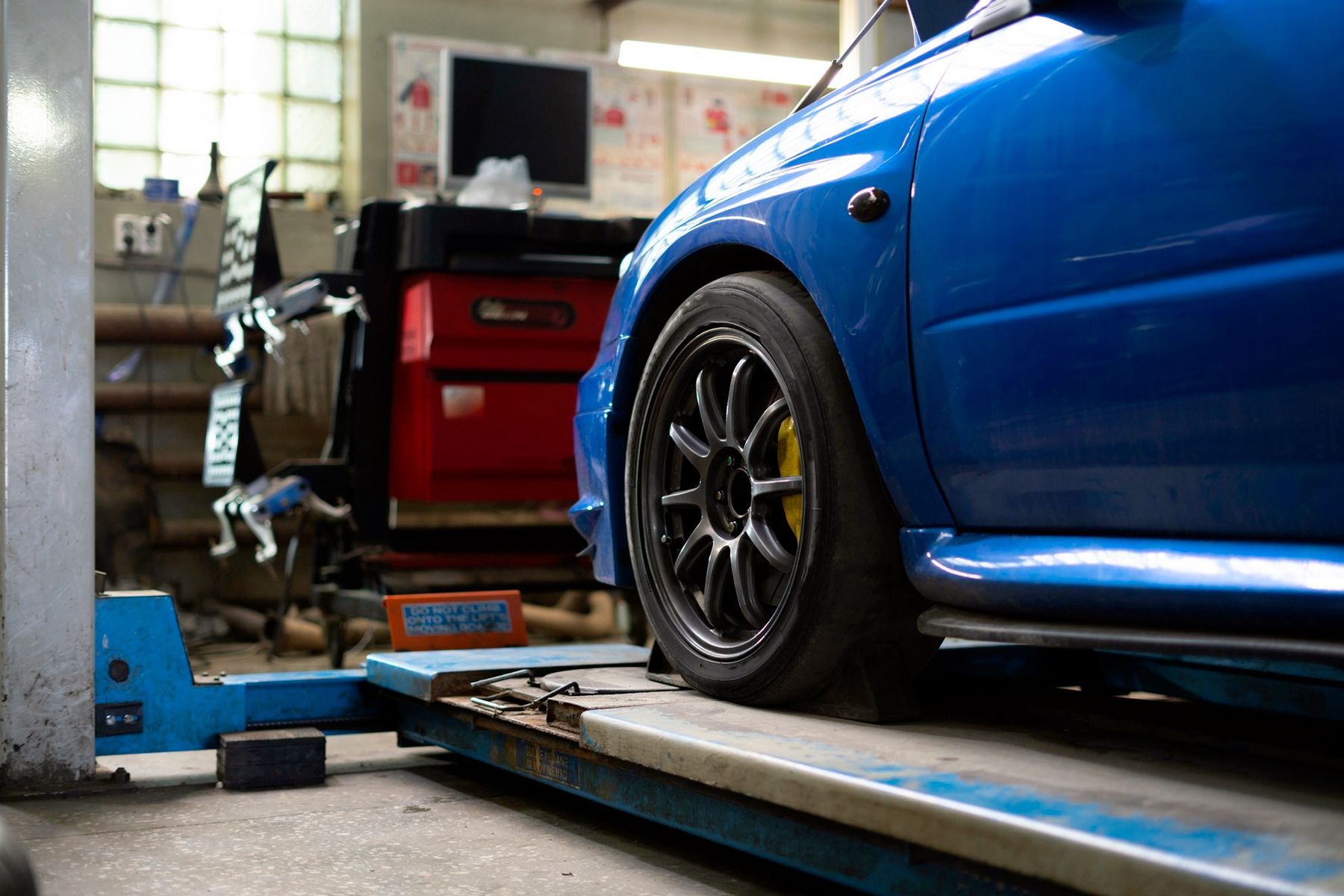Auto blu su un ponte sollevatore in un garage, con particolare attenzione alla ruota anteriore.