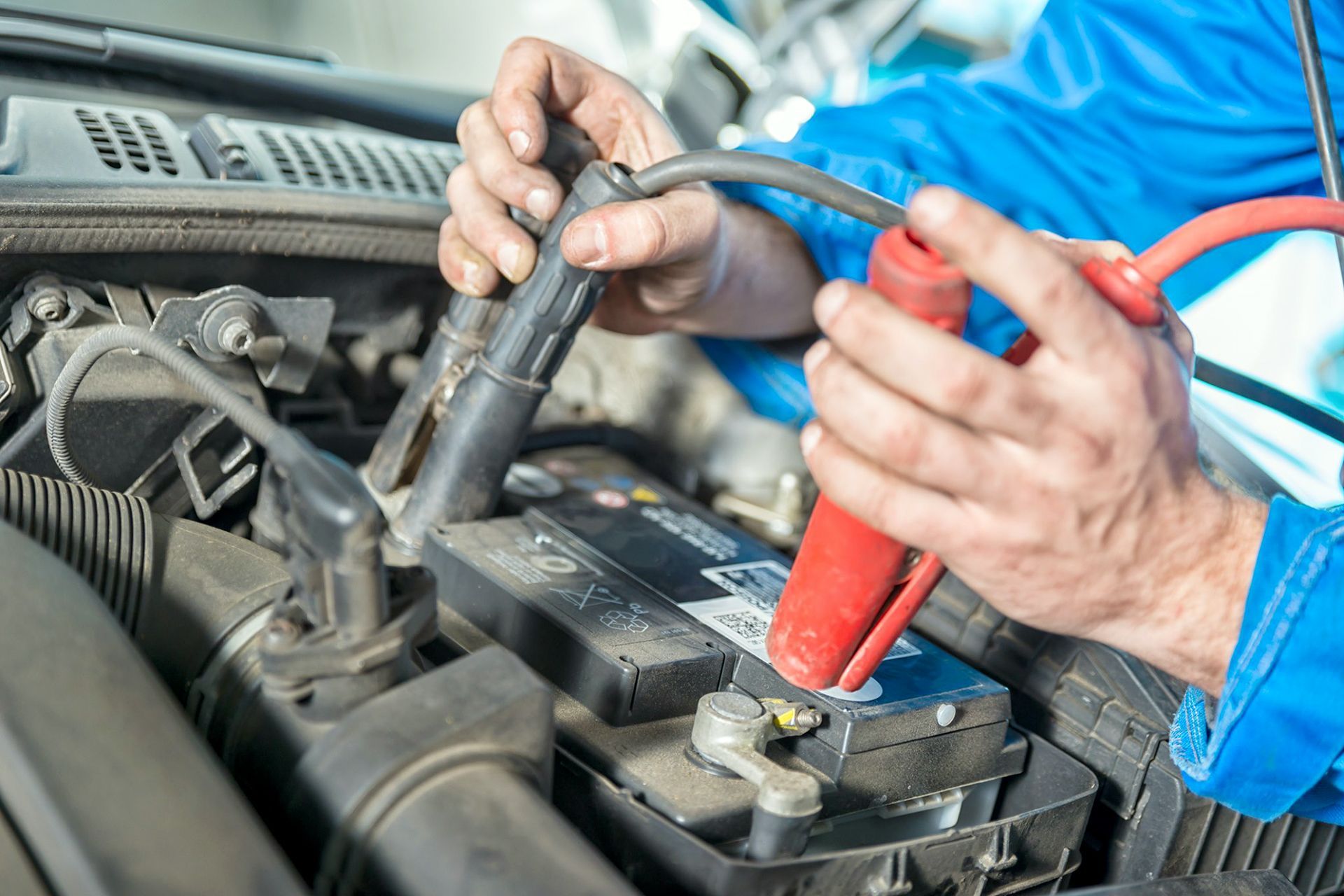 Mani che collegano i cavi di avviamento alla batteria di un'auto.