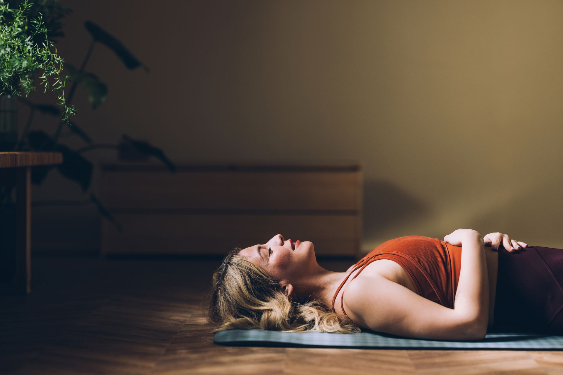 A woman is laying on a yoga mat on the floor.