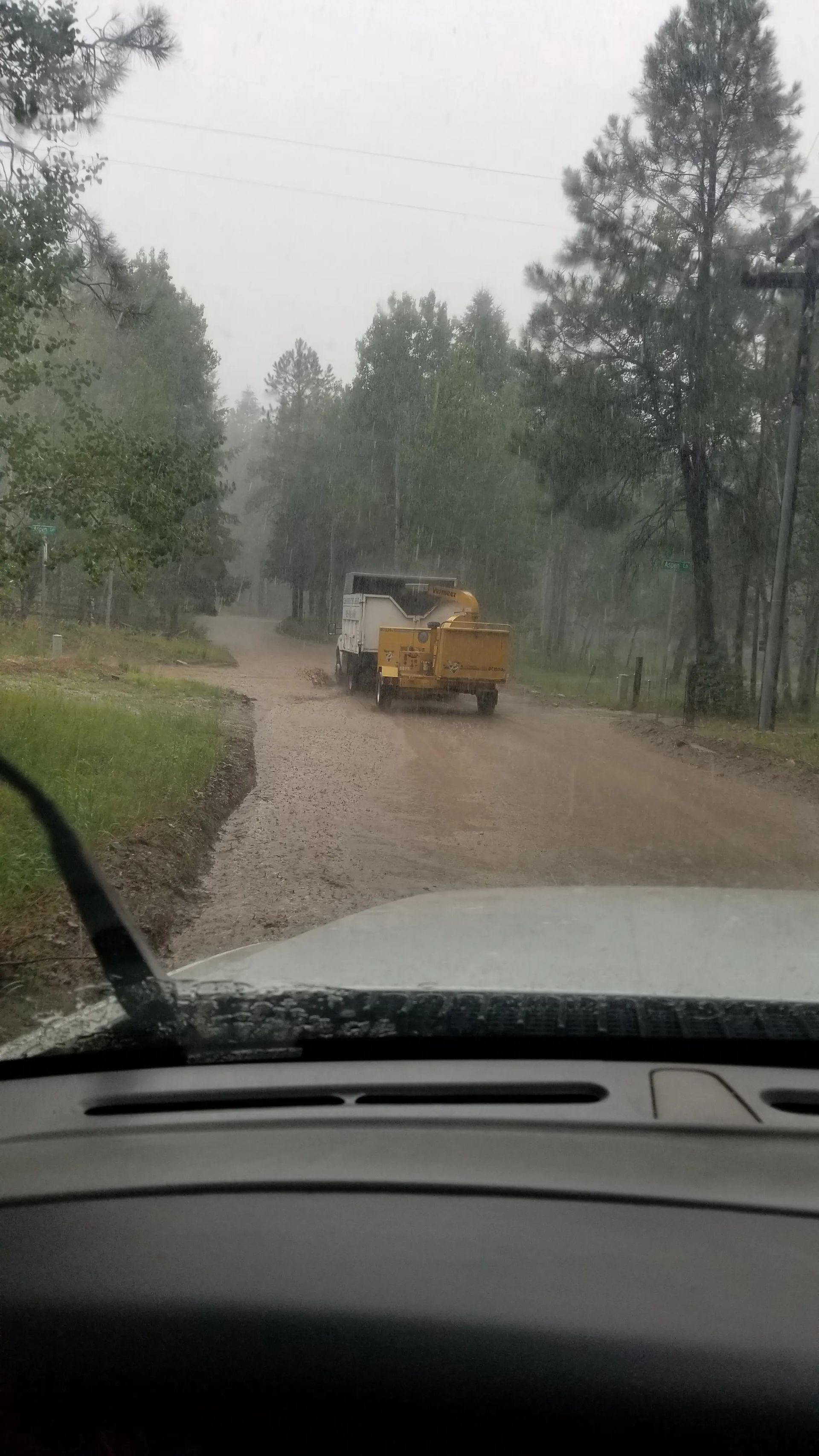 A truck is driving down a dirt road in the rain.