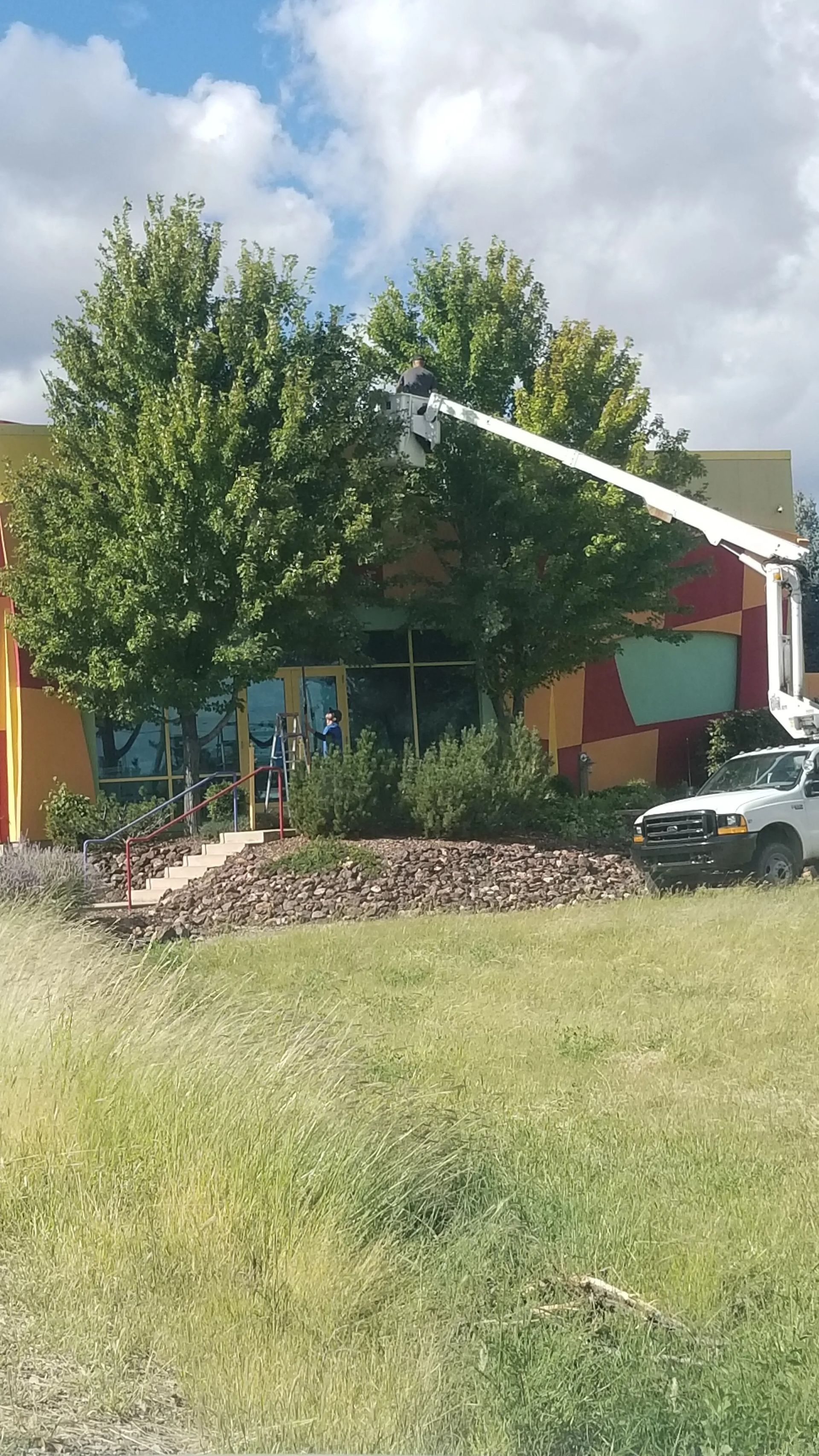 A white truck is parked in front of a building with a crane.